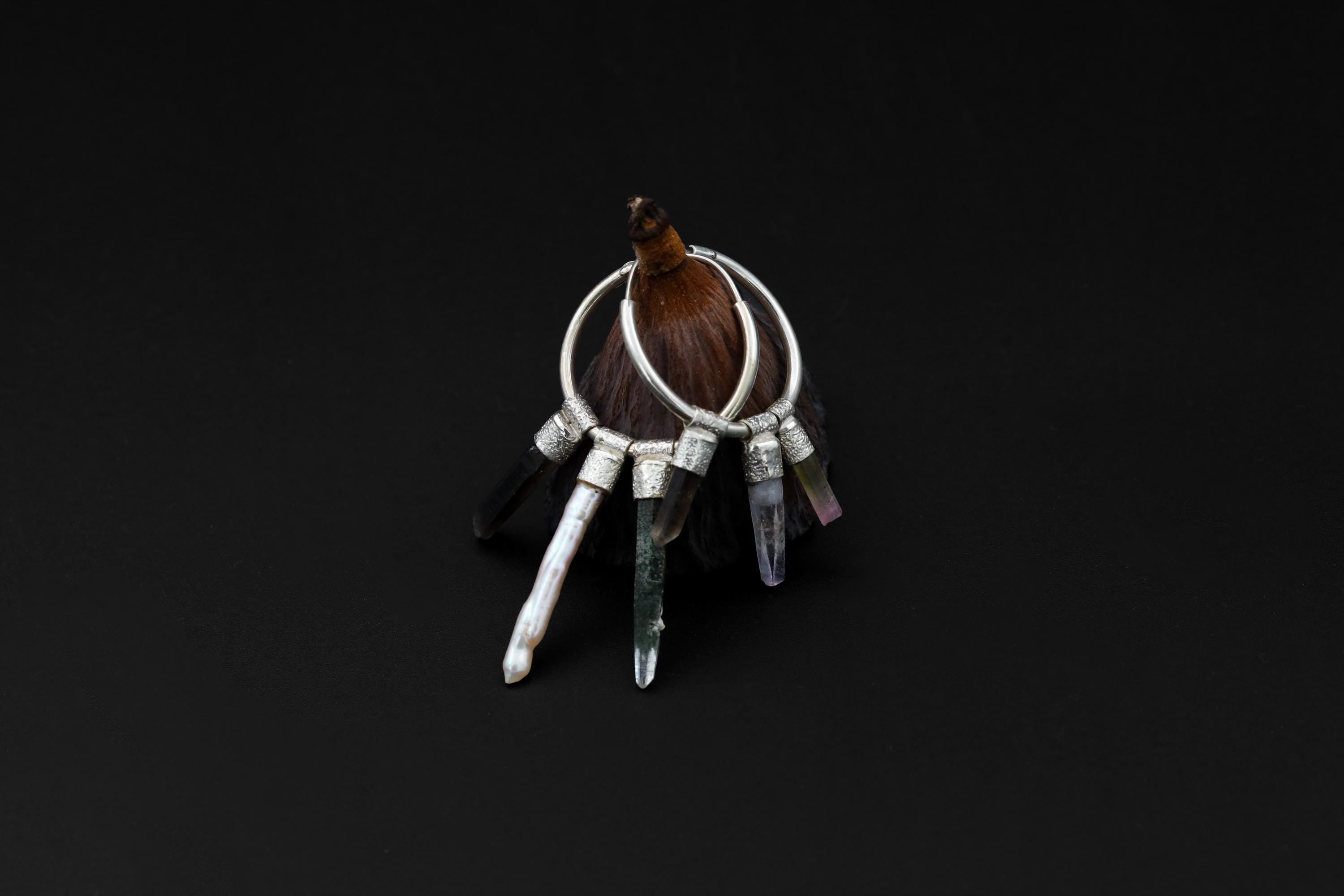 Celestial Gatherer crystal stack hoop earring shown on dark background with Pearl and raw gemstone dangles.