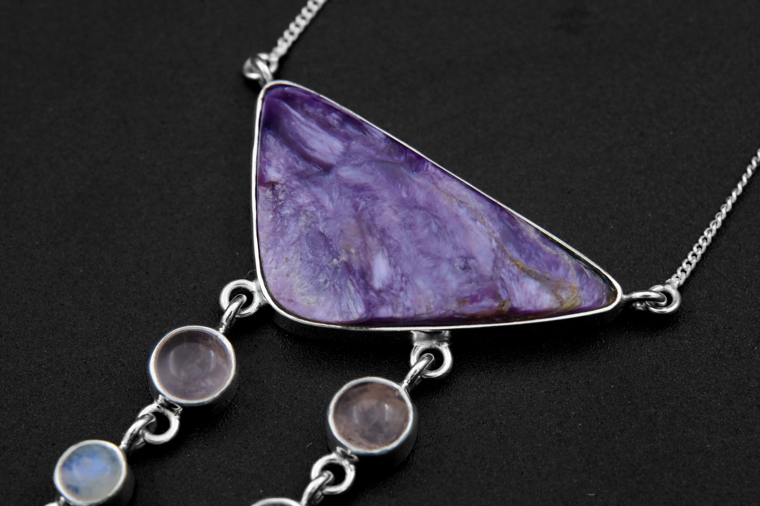Close-up of triangular Chlorite cabochon in an open-back sterling silver bezel with purple and white mineral swirls.