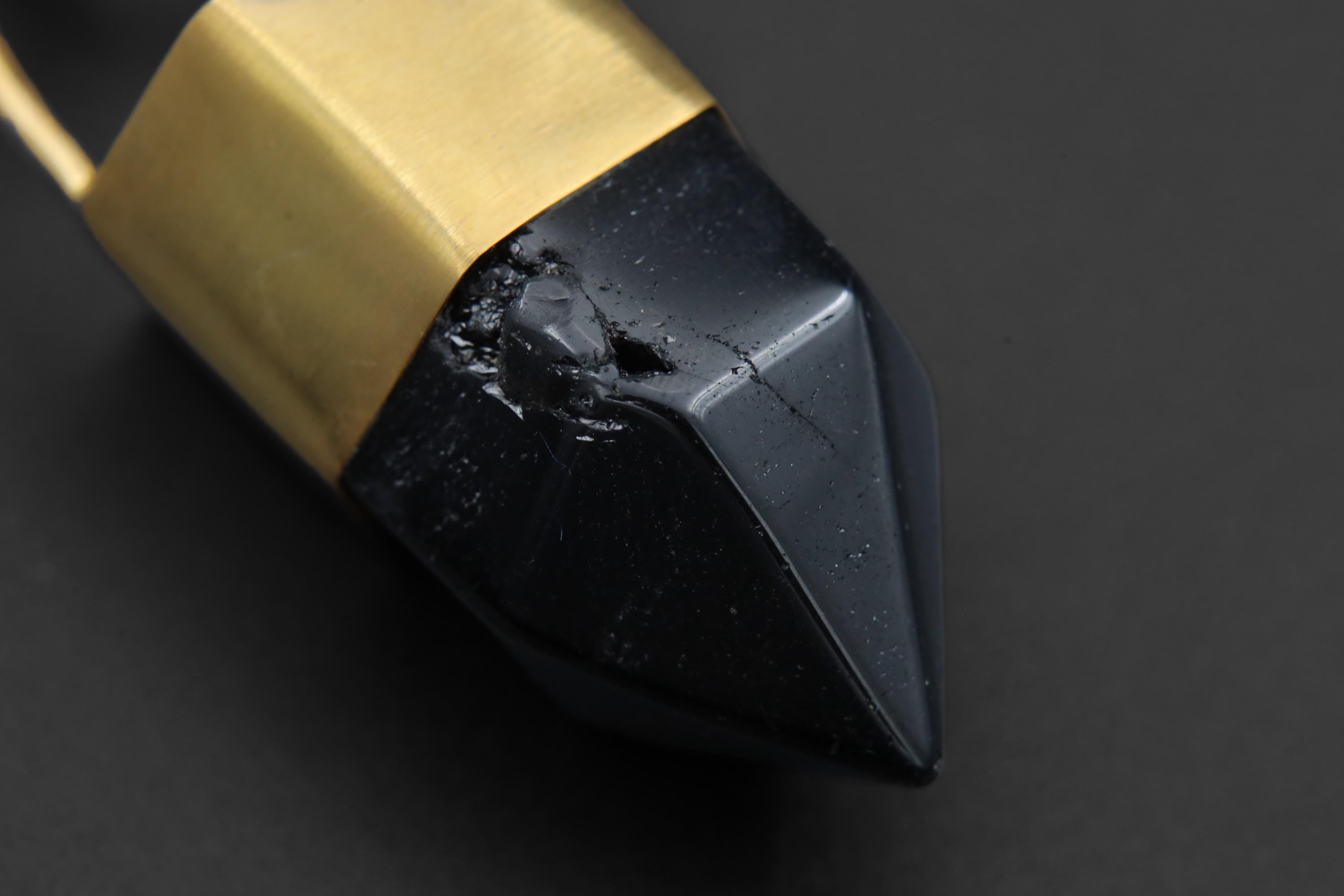 Close-up of dark Smoky Quartz point pendant showing polished crystal facets, gold-plated cap, and strong black-gold contrast.
