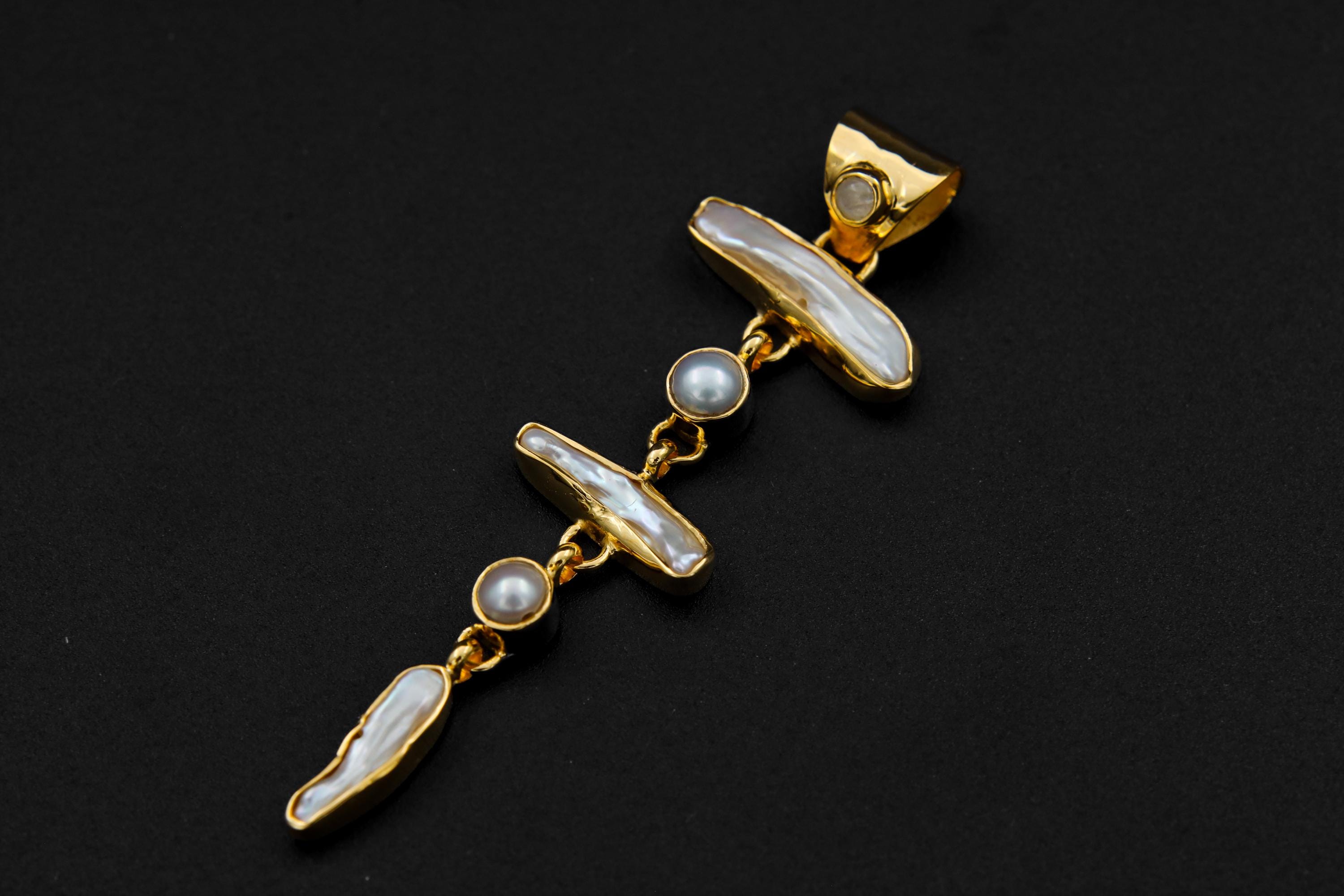 Blue Moonstone and Baroque Pearl cascade pendant shown on dark background with polished gold-plated silver setting.