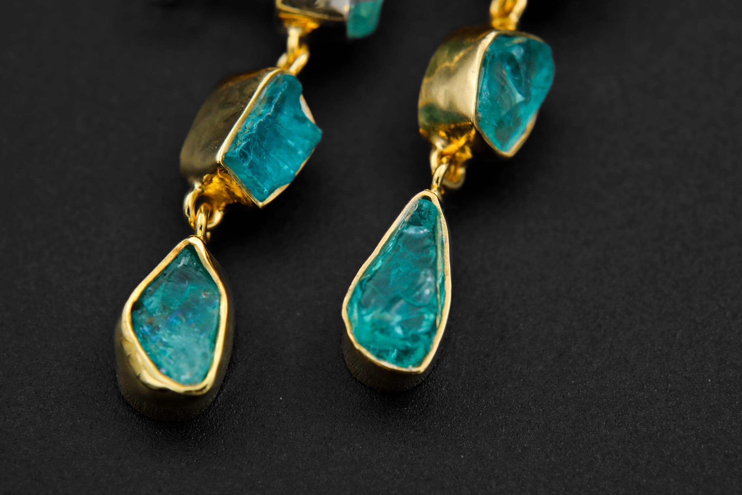 Detail view of gold-plated Blue Apatite earrings showing organic handmade settings and moving teardrop crystal drops.