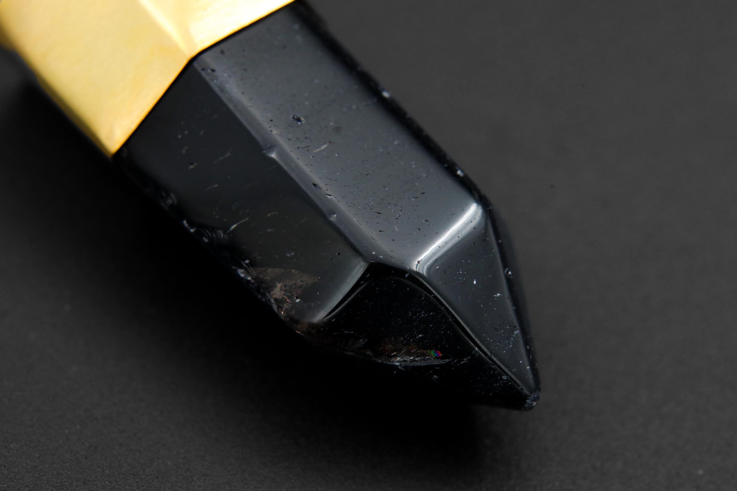 Close-up of dark Smoky Quartz point showing polished facets, deep smoky tone, and gold-plated bronze cap.