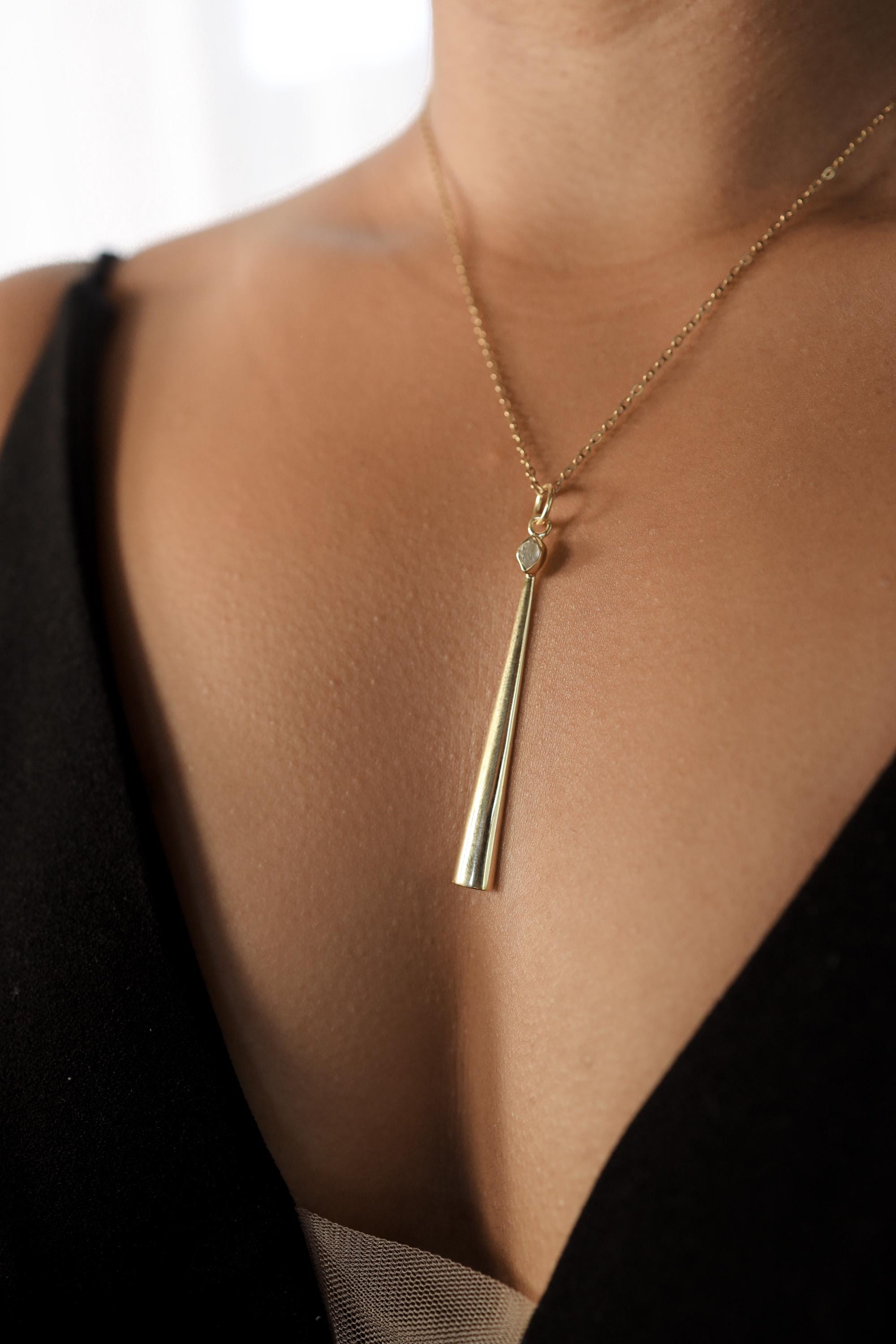 Detail view of long gold-plated spoon pendant showing Herkimer Diamond crown and polished scoop body.