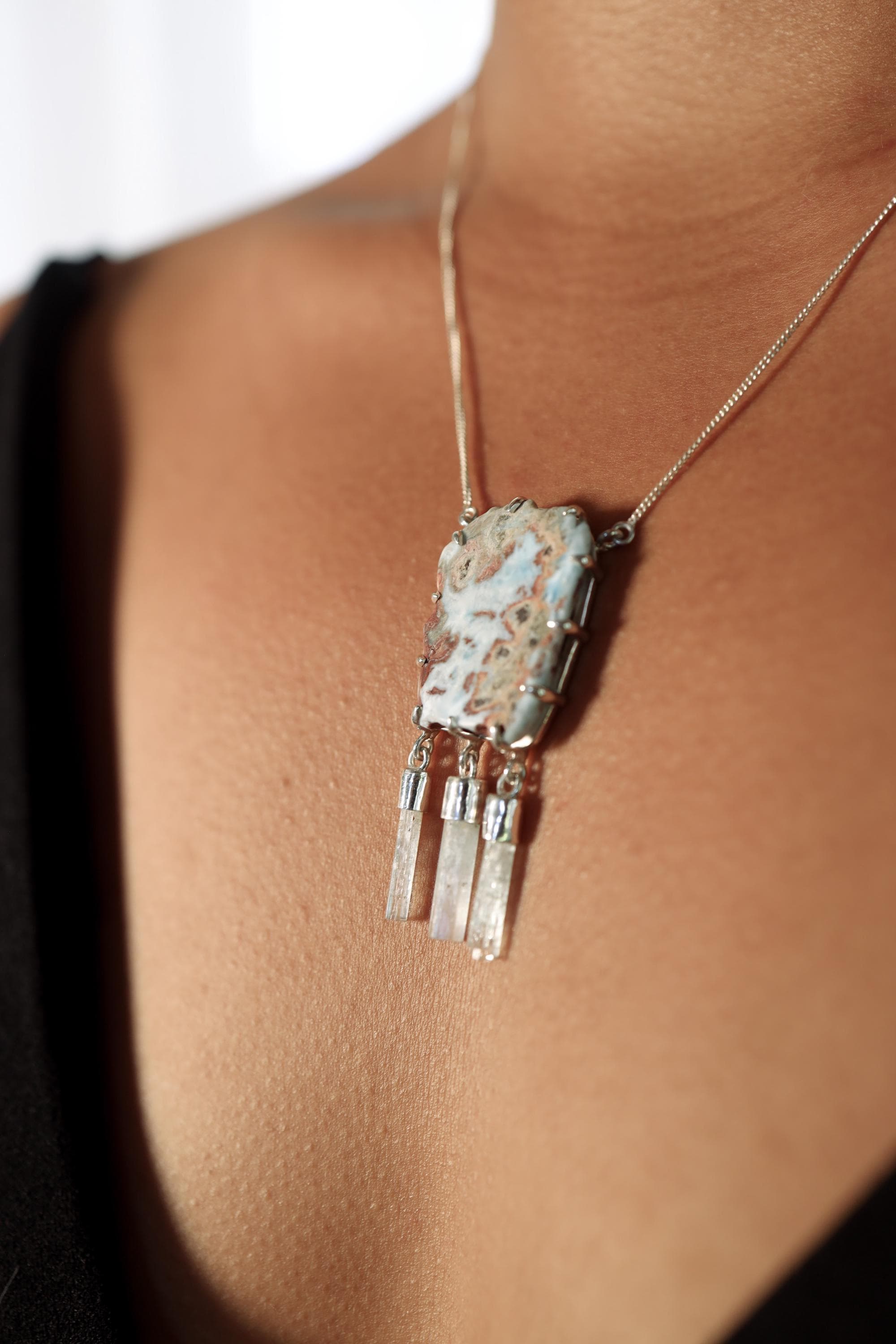 Larimar Aquamarine ocean necklace shown worn on the chest, with a bold blue centre stone and three moving crystal dangles.