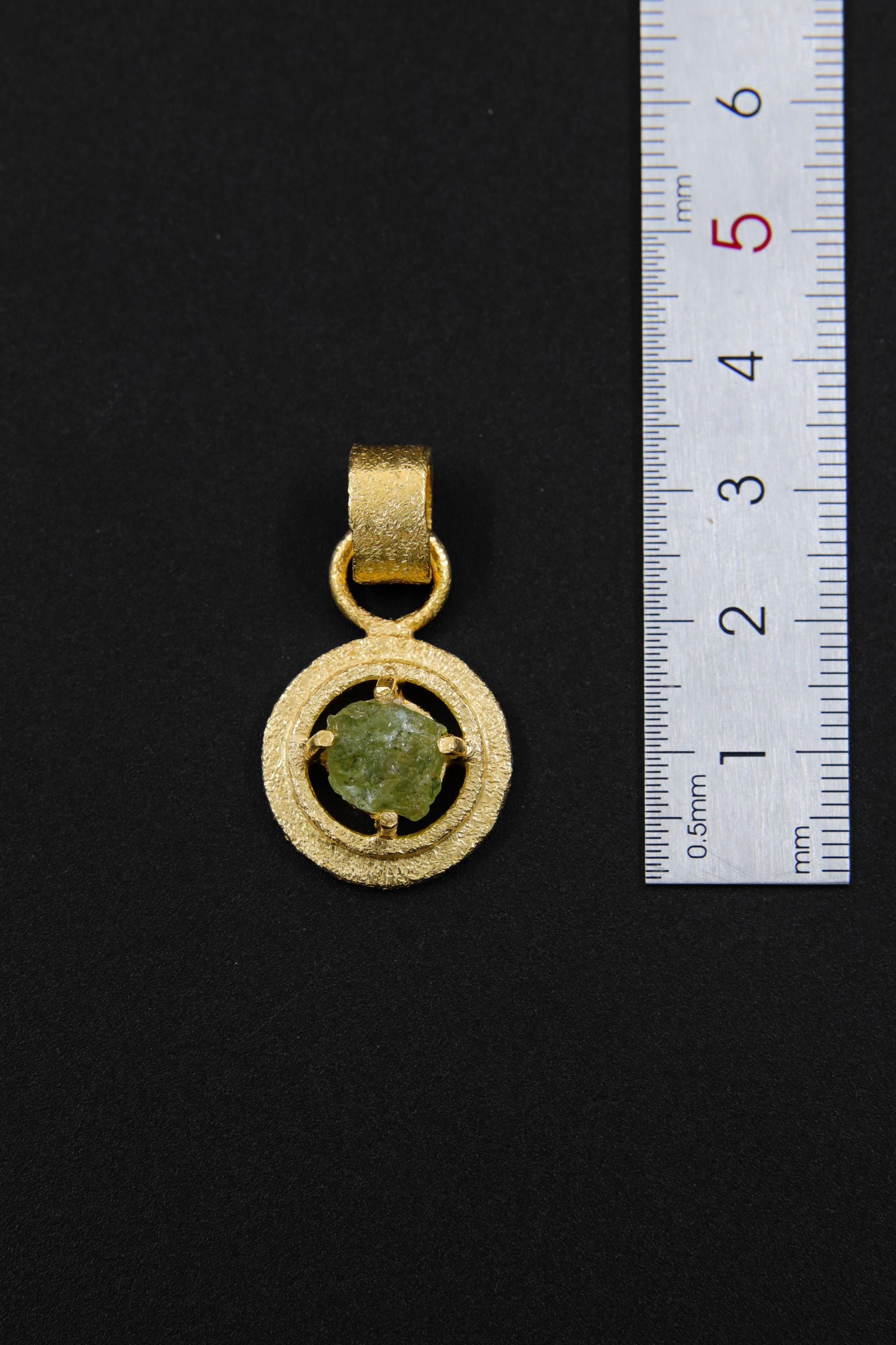Raw Peridot claw pendant shown beside a ruler for scale, measuring approximately 3 cm total length including bail.