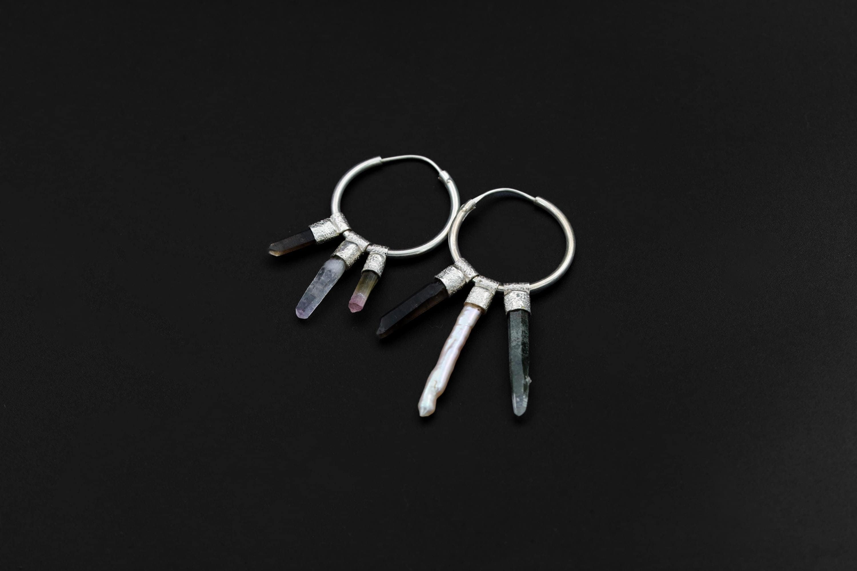 Celestial Gatherer crystal stack hoop earrings shown on dark background with sterling silver hoops and mixed gemstone dangles.