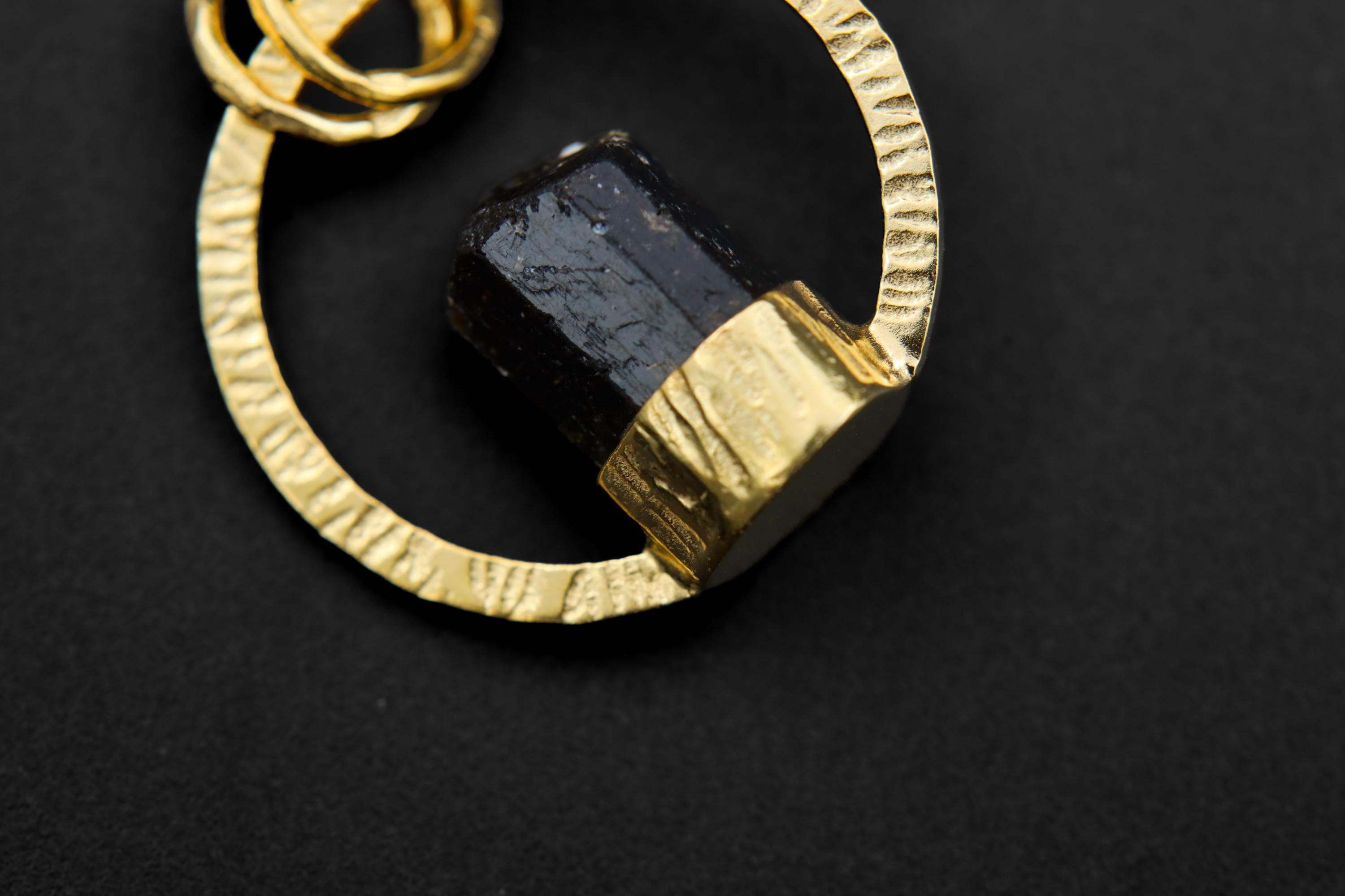 Detail view of Himalayan Dravite Tourmaline set into a textured gold-plated halo pendant with balanced double bails.