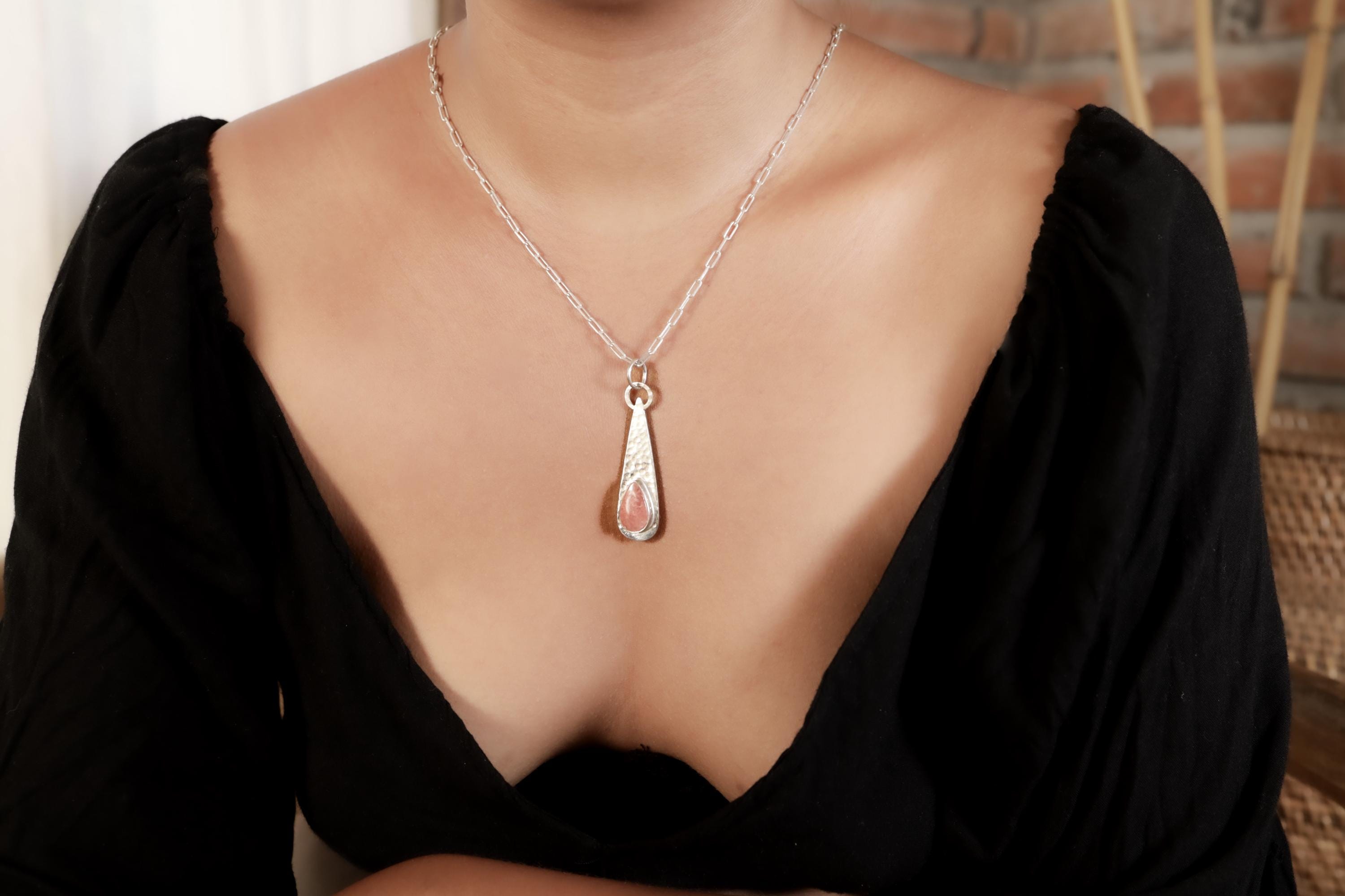 Compassion Flame Rhodochrosite pendant worn on a model with teardrop sterling silver frame and rose-pink stone.