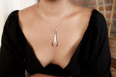 Compassion Flame Rhodochrosite pendant worn on a model with teardrop sterling silver frame and rose-pink stone.