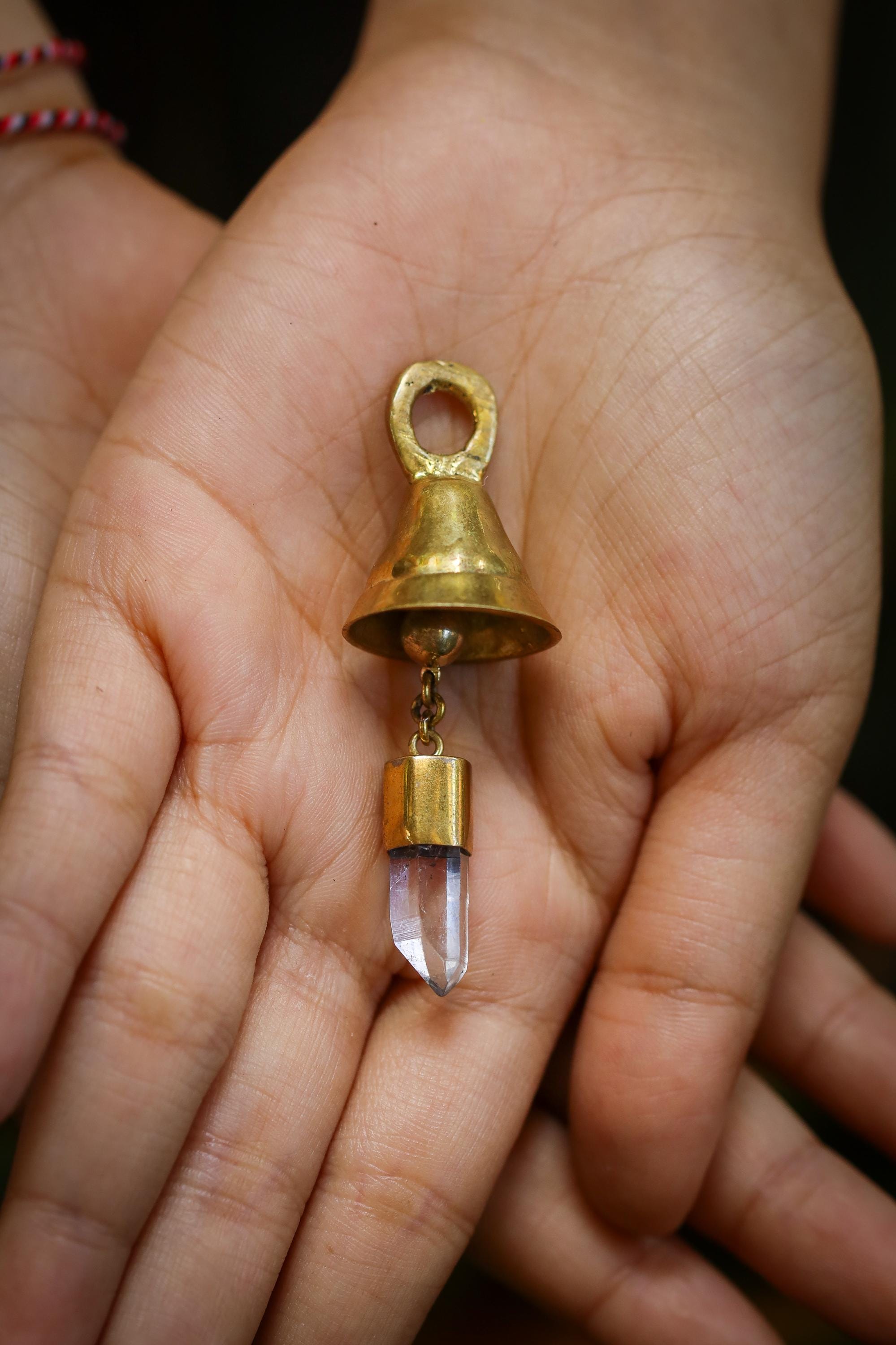 Clear Quartz Mini Prayer Bell held in hand with 18k gold-plated bronze body and tiny crystal point.