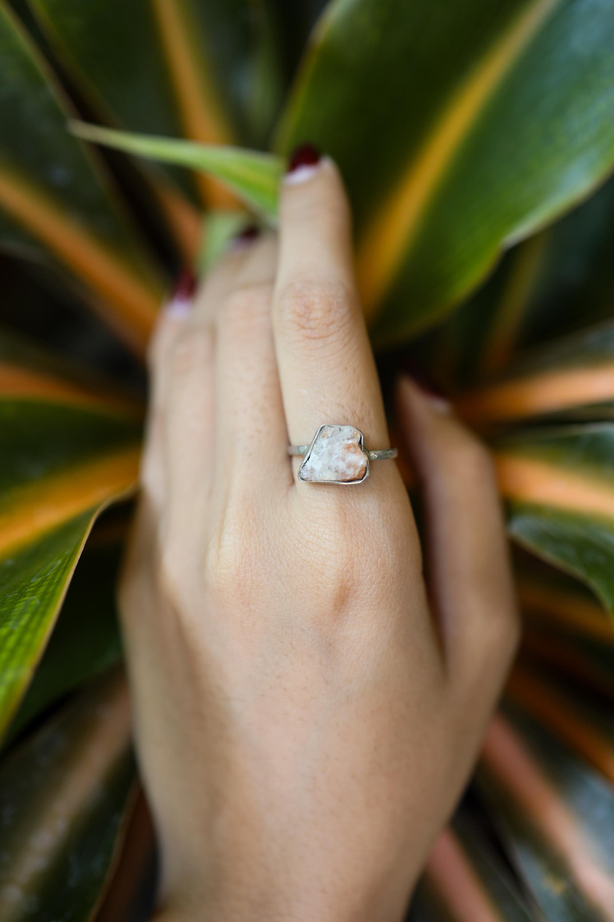 Sunstone sterling silver ring shown on clear quartz, with pale golden feldspar stone and handmade polished silver setting.