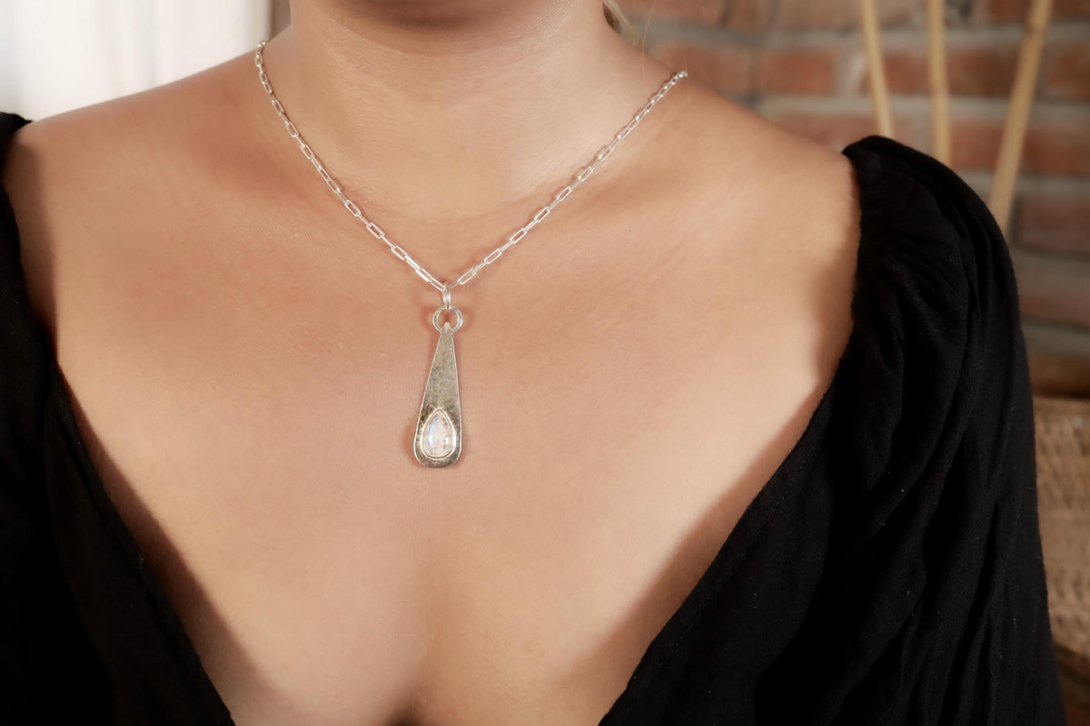 Blue Moonstone teardrop pendant worn on a model with hammered sterling silver and soft luminous gemstone centre.
