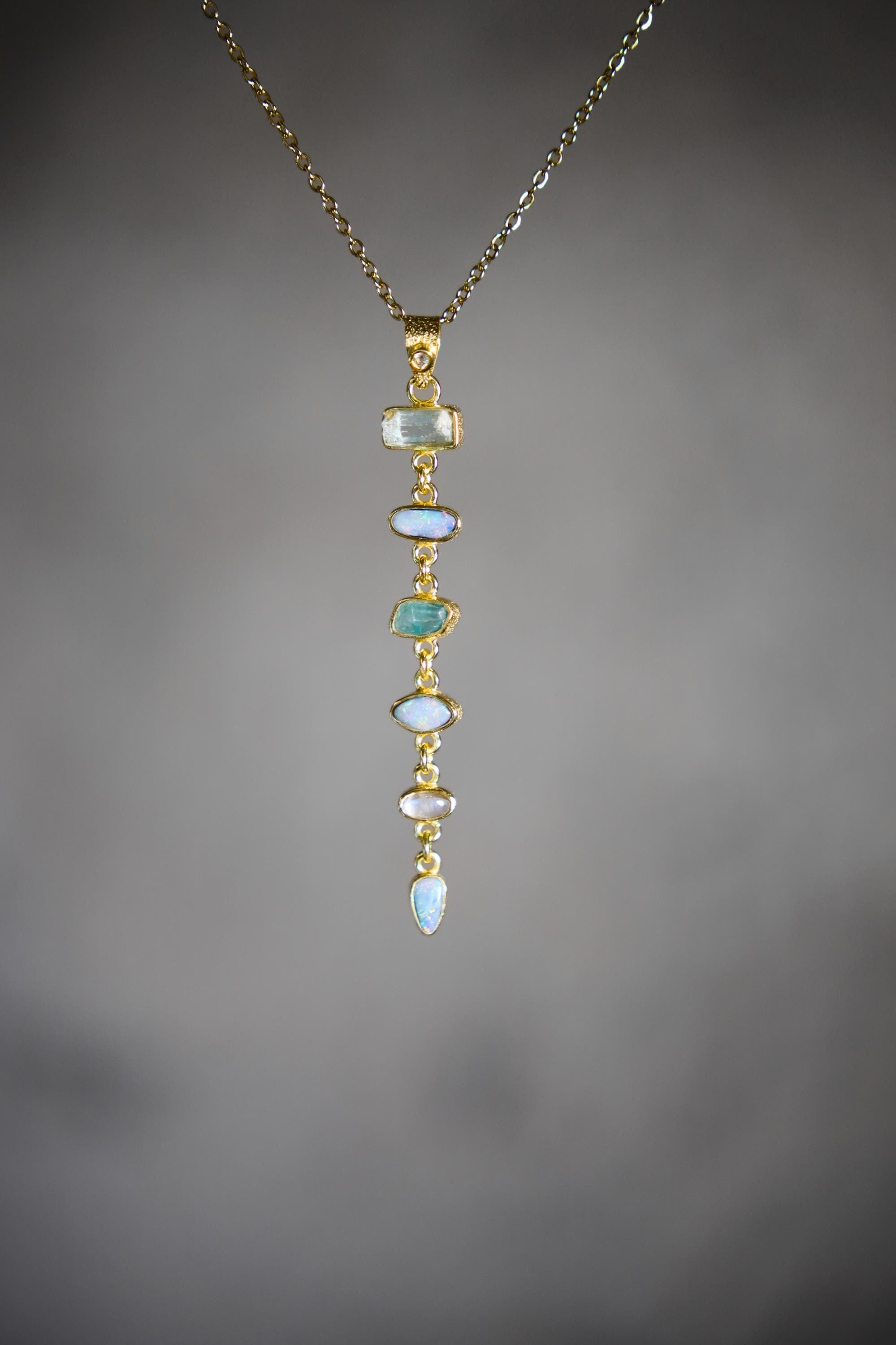 Zircon Aquamarine Australian Opal and Blue Moonstone pendant on a dark background, showing long linked gemstone cascade.