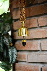 Smoky Quartz prayer bell hanging near brick wall with 18k gold-plated bronze finish and grounding crystal detail.