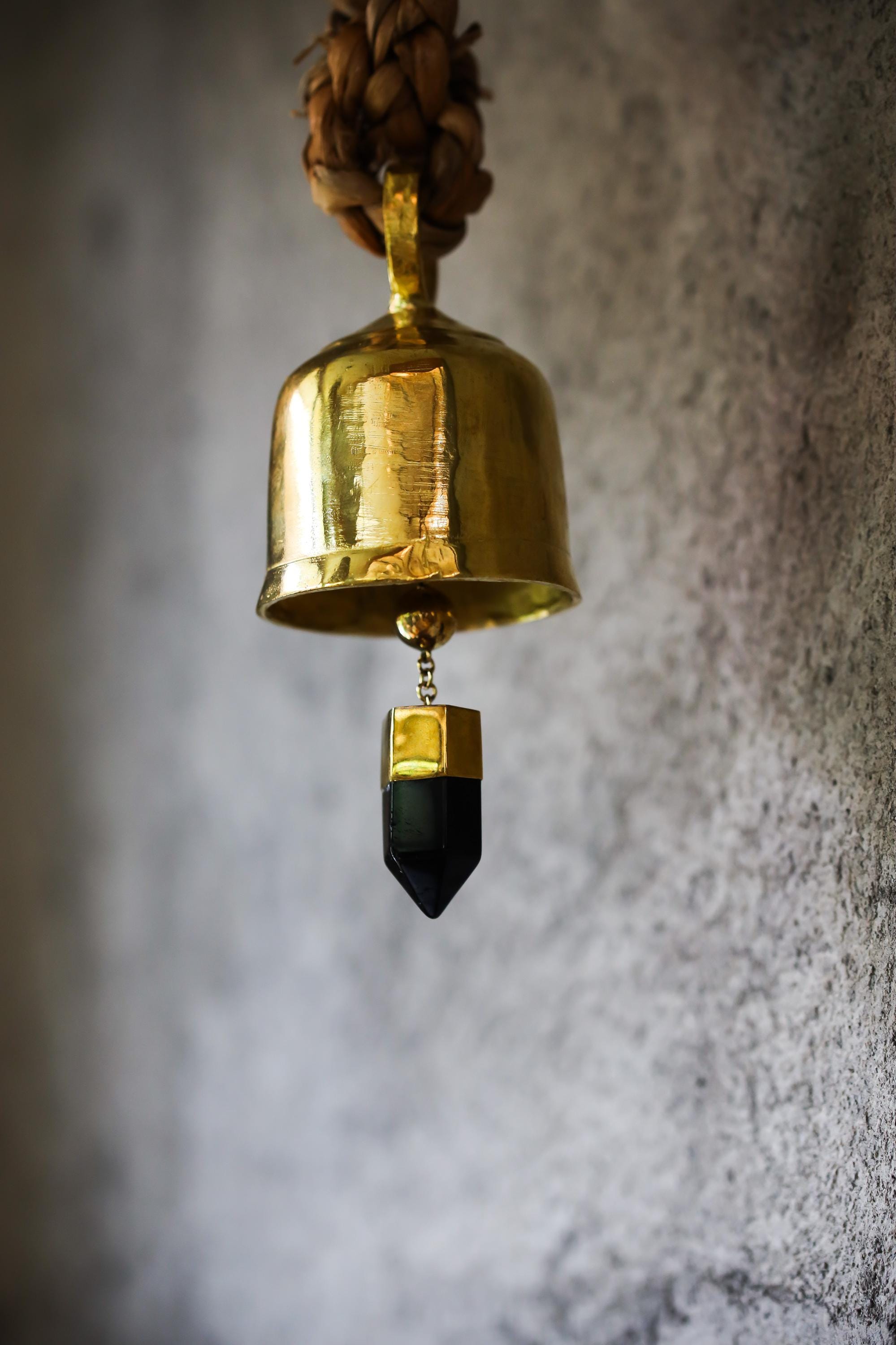 Smoky Quartz Gold Plated Prayer Bell hanging against grey wall with warm ceremonial shine.