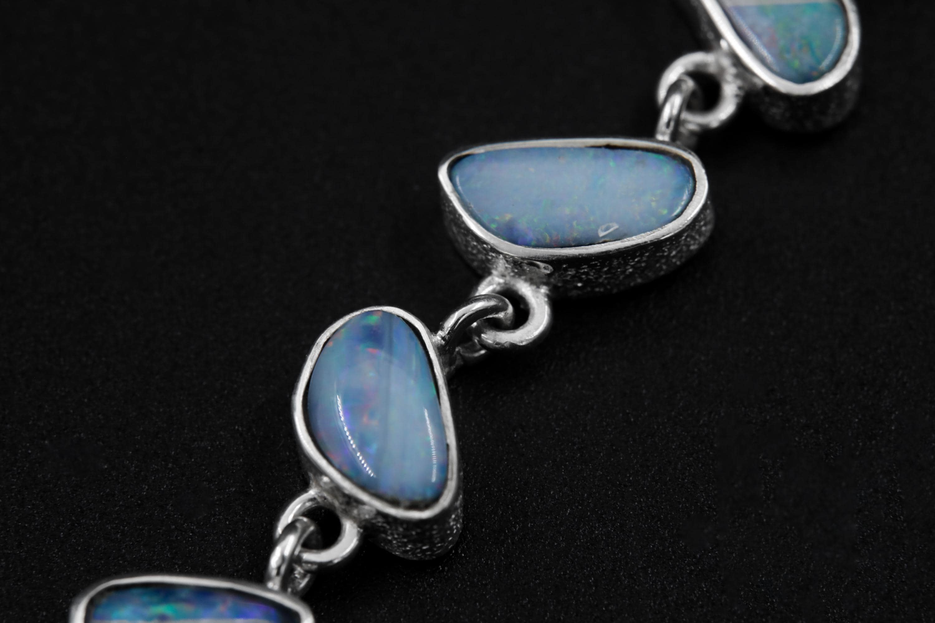 Close-up of Australian Opal Doublet droplets in textured sterling silver, showing blue and pink colour play.