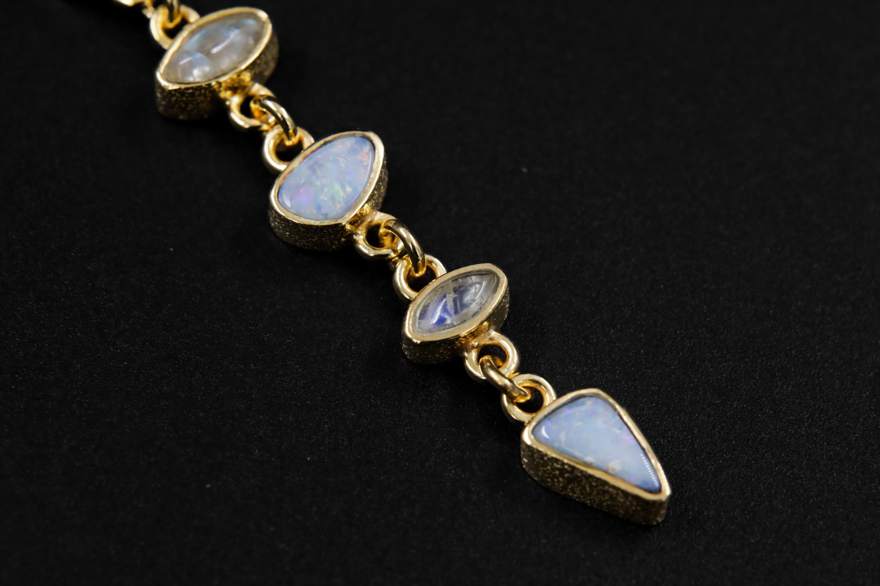 Detail view of Zircon Aquamarine Opal Moonstone pendant showing blue gemstone colour, gold-plated settings, and linked cascade structure.