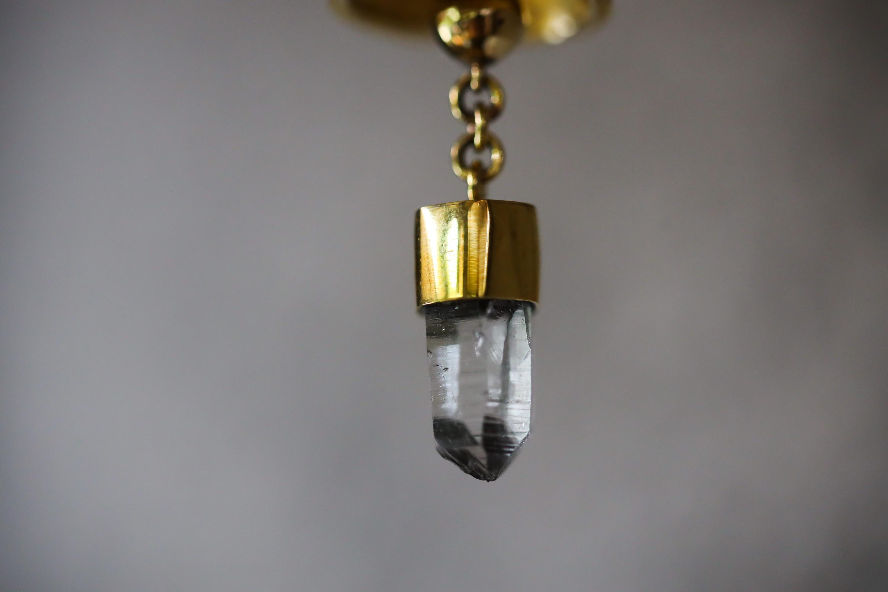 Close-up of Clear Quartz point suspended inside gold-plated bronze prayer bell with bright handmade finish.