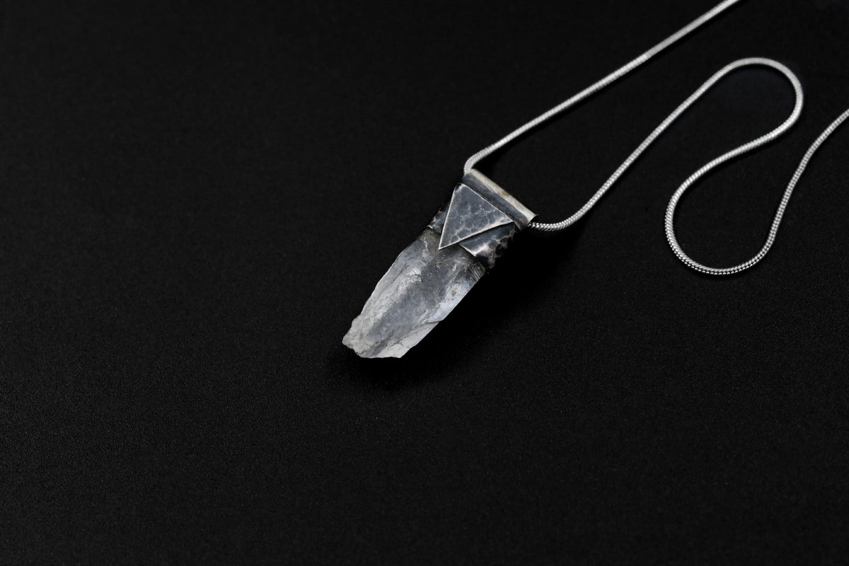 Water Clear Nepalese Inclusion Quartz Pendant shown on black background with oxidized sterling silver cap and black cotton necklace.