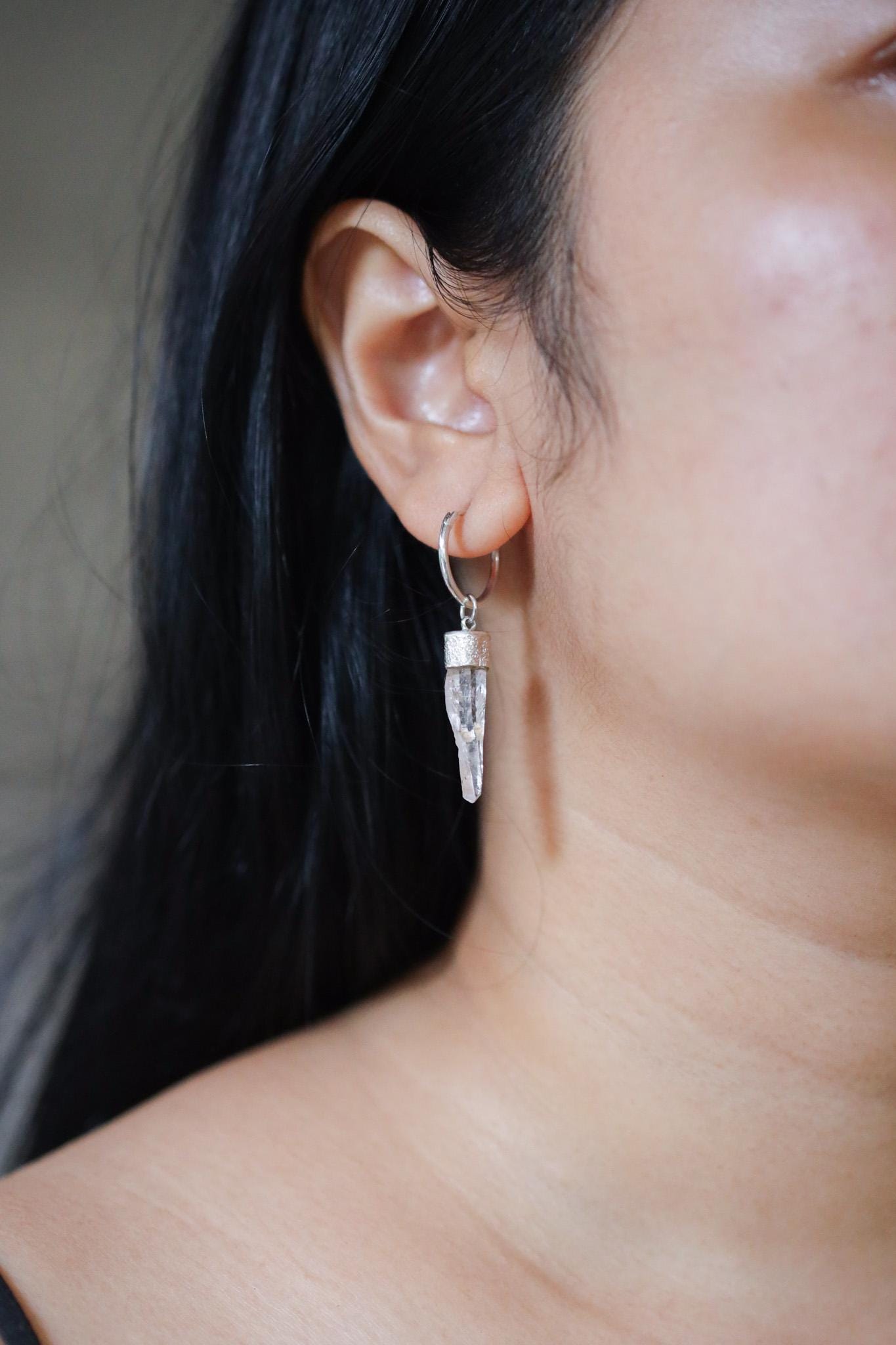 Clear Quartz single earring shown worn on a model, with slim crystal drop and polished silver hoop.