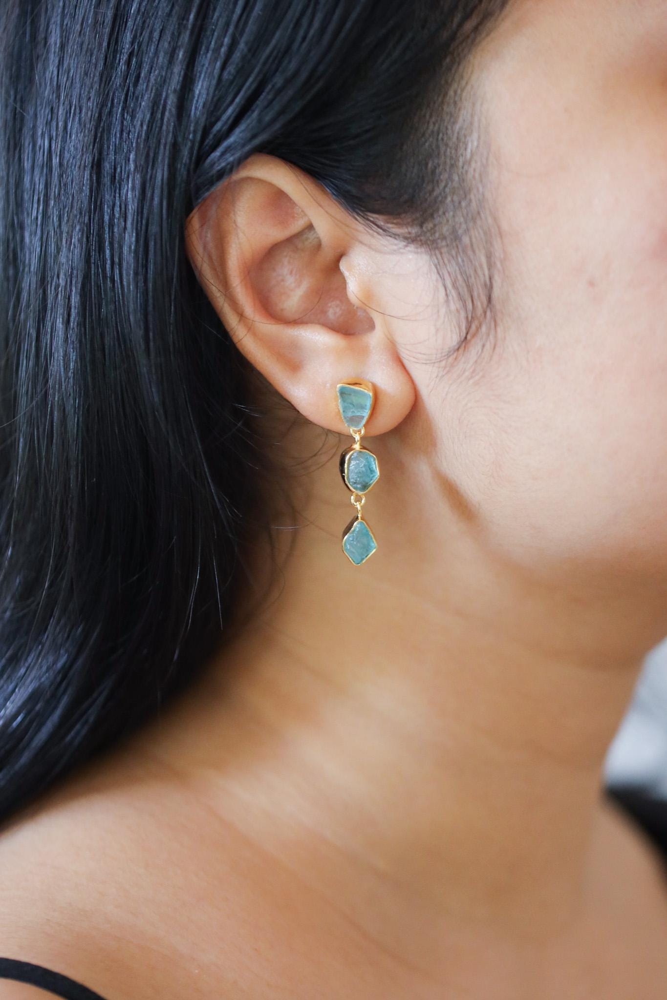 Blue Apatite gold-plated sterling silver earrings shown worn on the ear as expressive Throat Chakra crystal dangles.