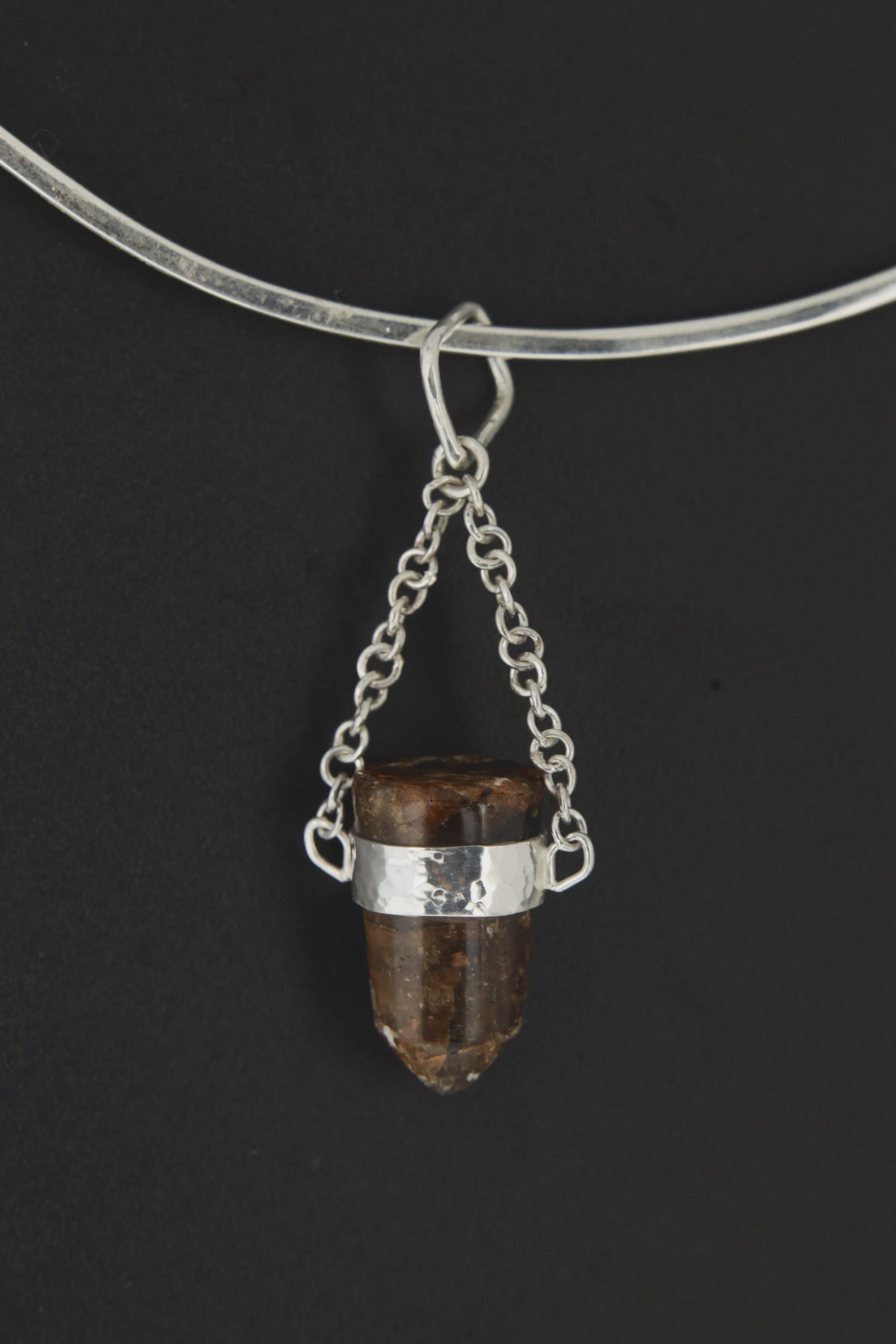 Bullet Brown Tourmaline Dravite Pendant shown on black background with silver choker and compact grounding crystal form.