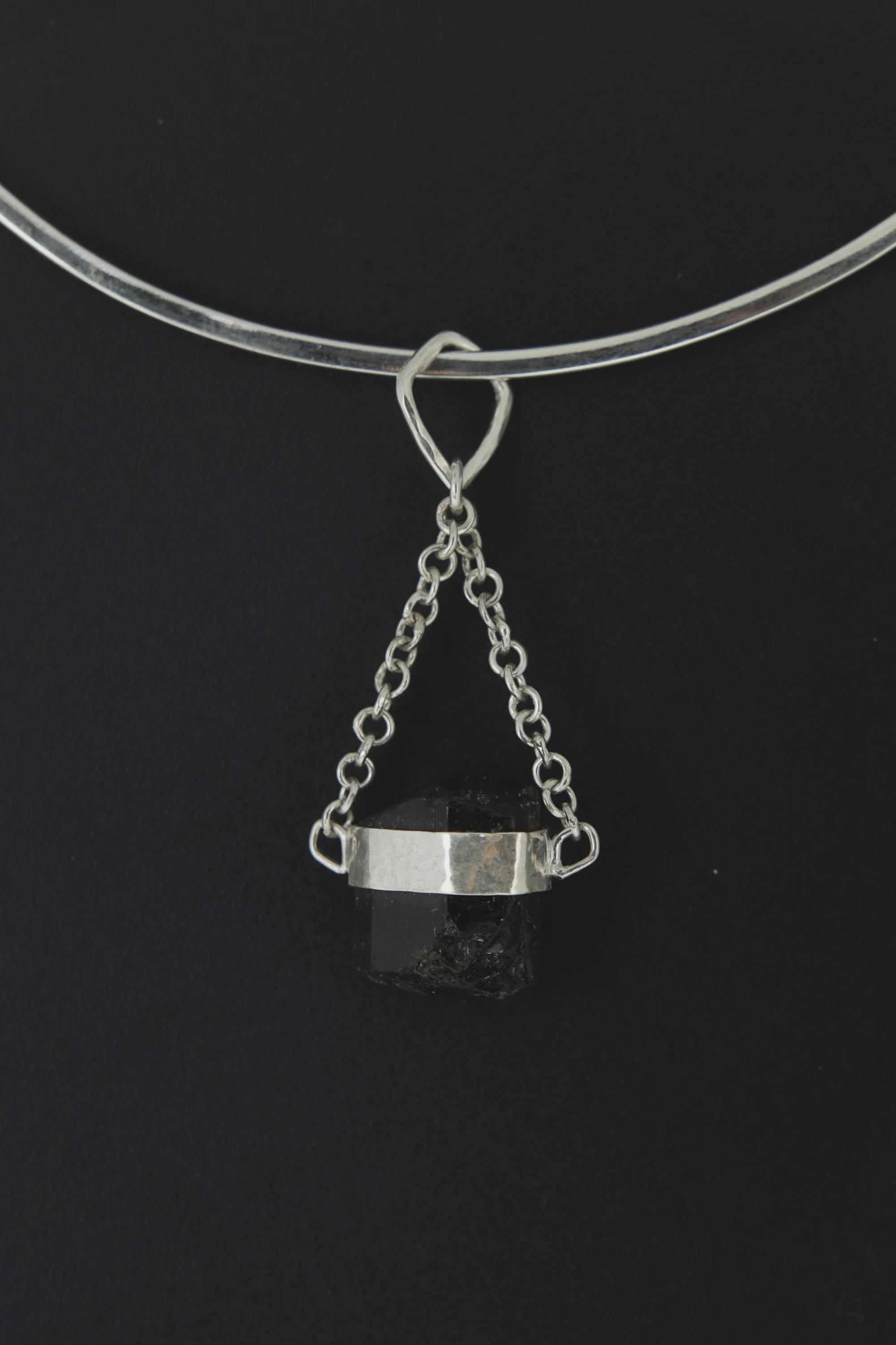 Black Tourmaline pendant displayed on choker against dark background as a Root Chakra talisman.