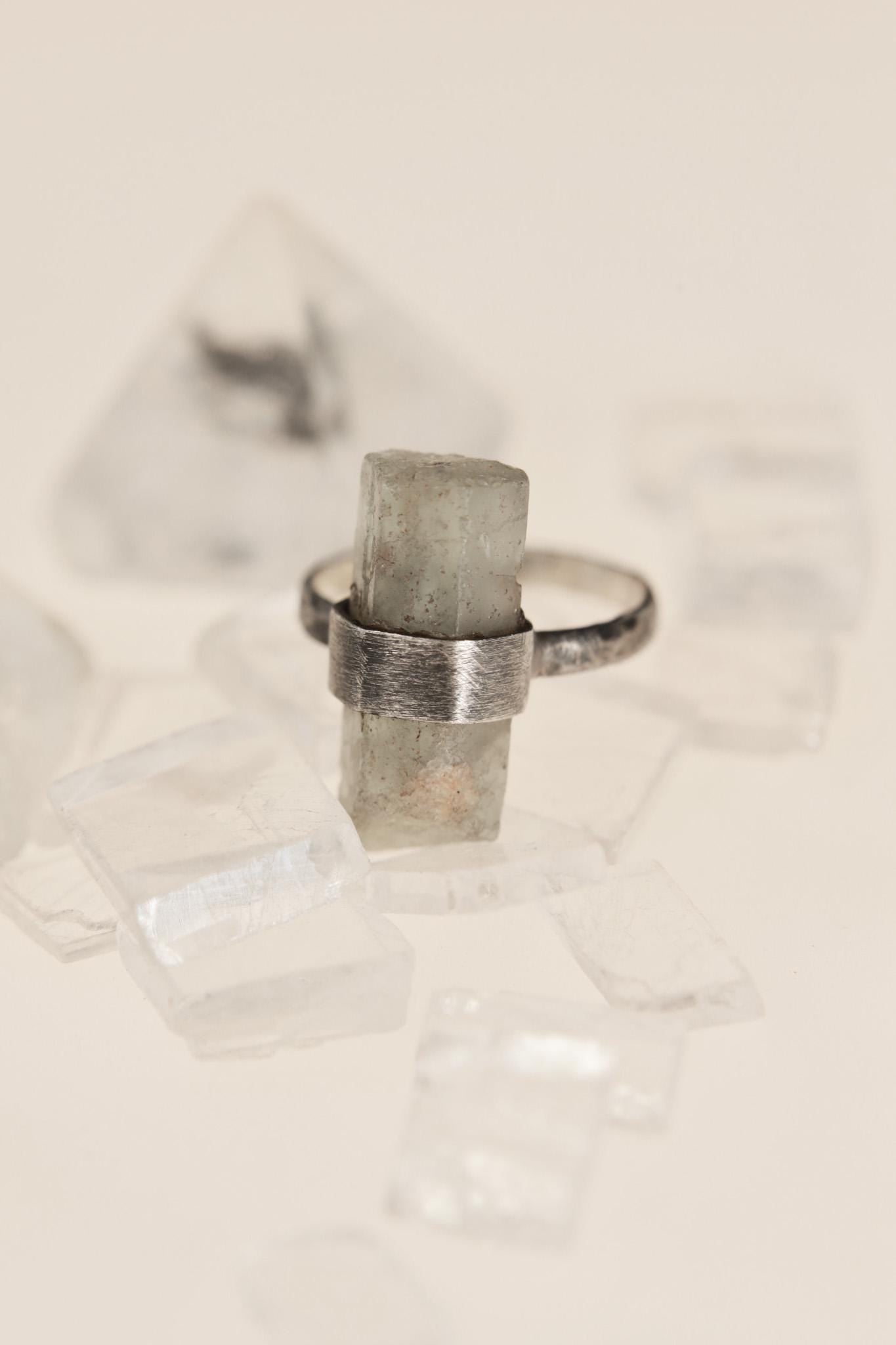 Raw Aquamarine ring displayed on crystal styling with hammered sterling silver band and brushed setting.