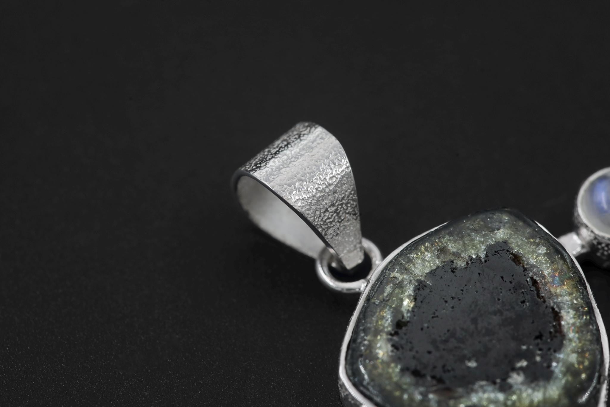 Close-up of bail and raw Green Tourmaline in a high-shine sterling silver pendant setting.