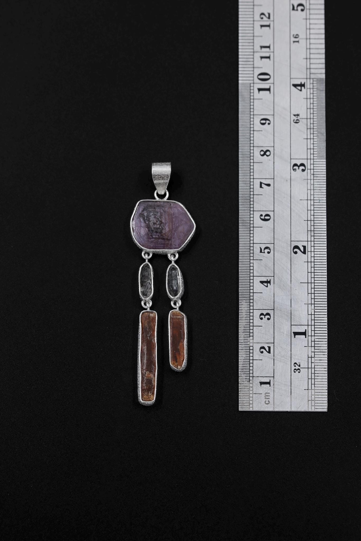 Ruby Flame Dreamcatcher pendant shown beside a ruler for scale, measuring approximately 7.5 cm long.