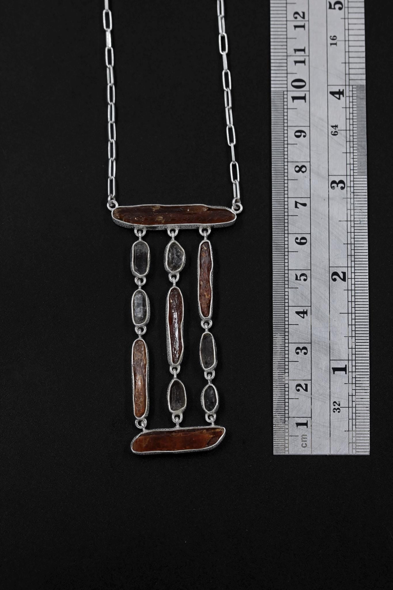 Flamepath Alignment necklace shown beside a ruler for scale, measuring approximately 6.5 cm pendant length.