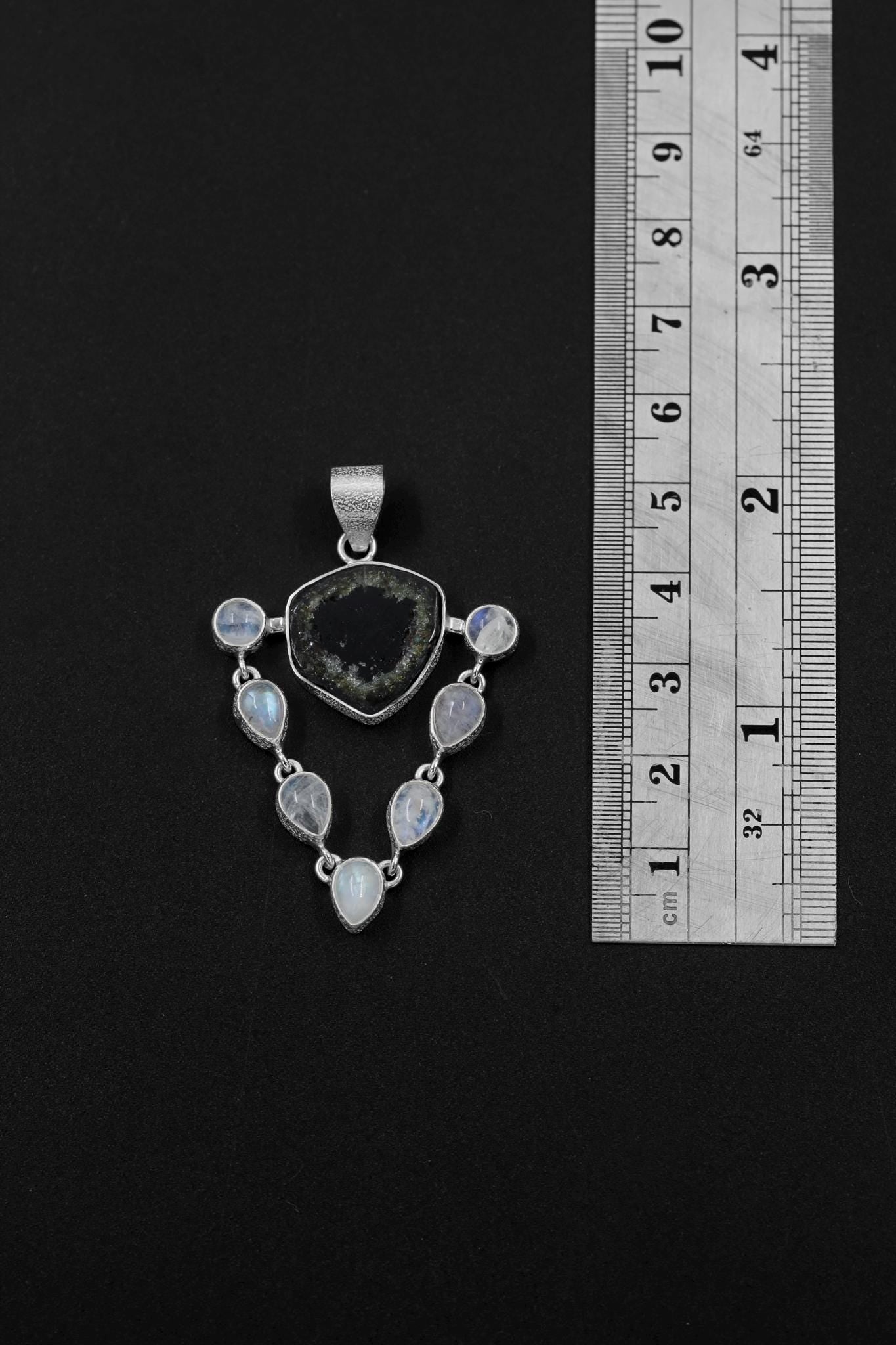Green Tourmaline Moonstone pendant shown beside a ruler for scale, with central triangular stone and teardrop Moonstone halo.