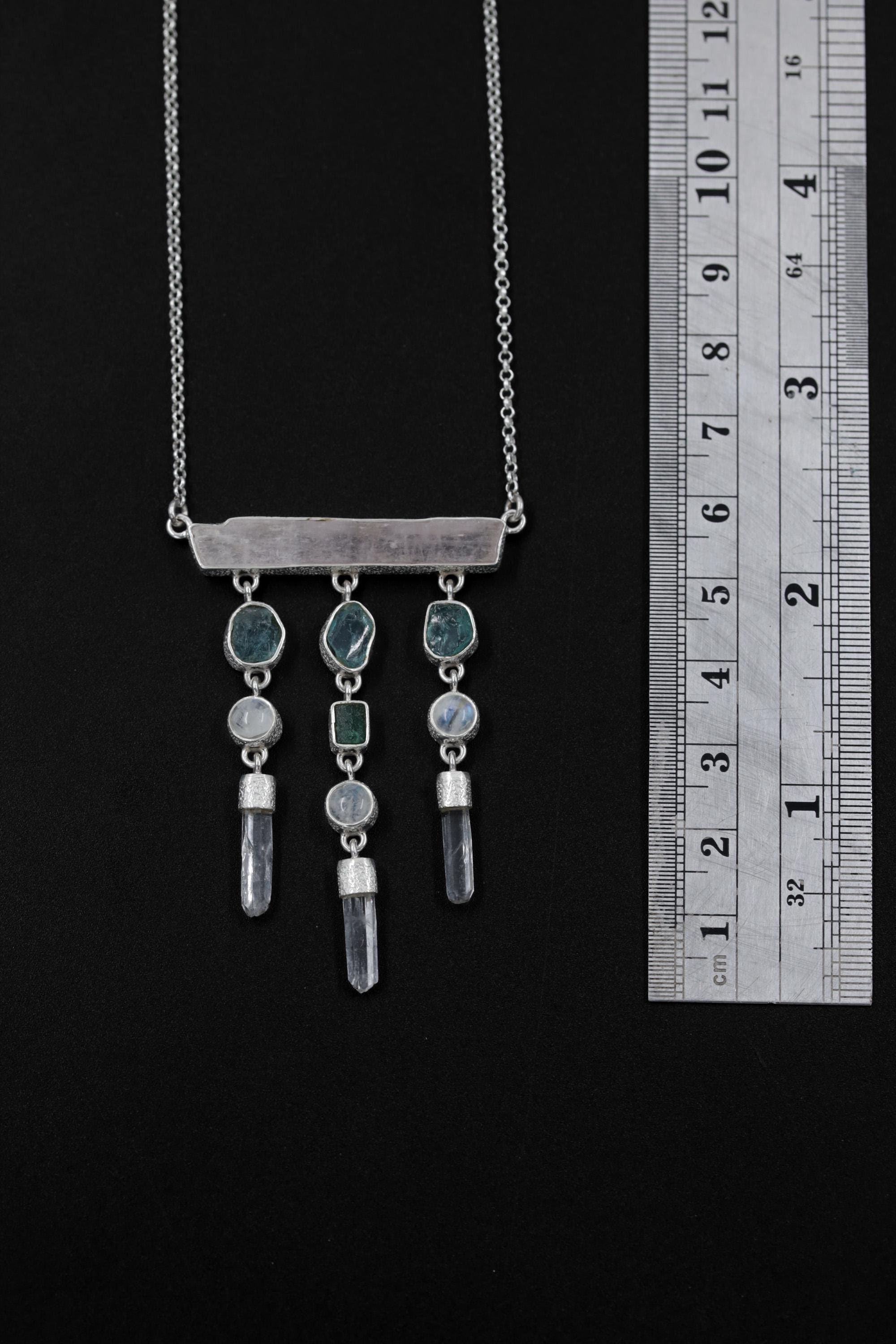 Aurora Alignment talisman shown beside a ruler for scale, with Pink Kunzite bar and three dangling crystal strands.
