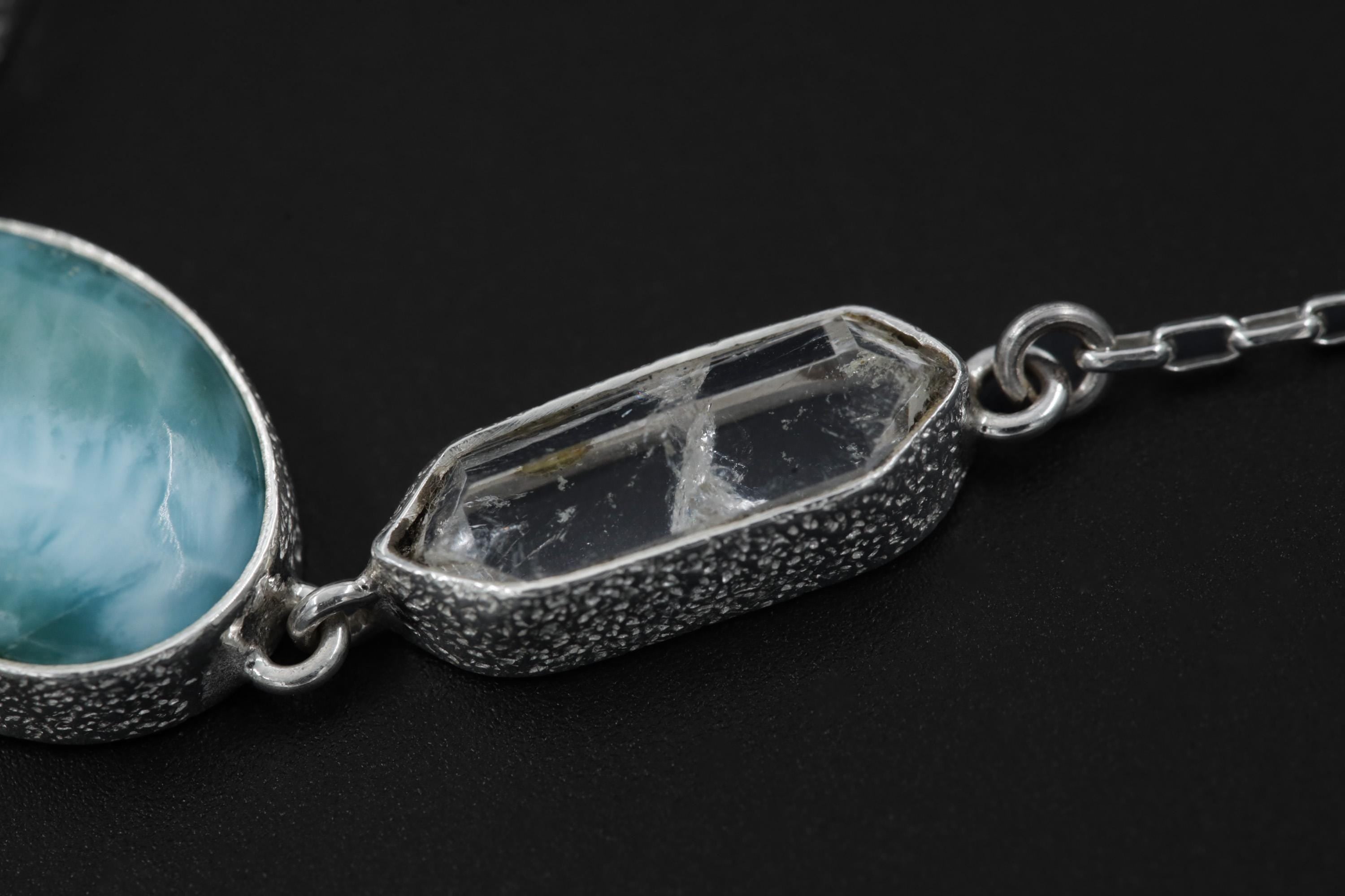 Close-up of Larimar and Clear Quartz in a textured sterling silver ocean necklace with blue gemstone centre.