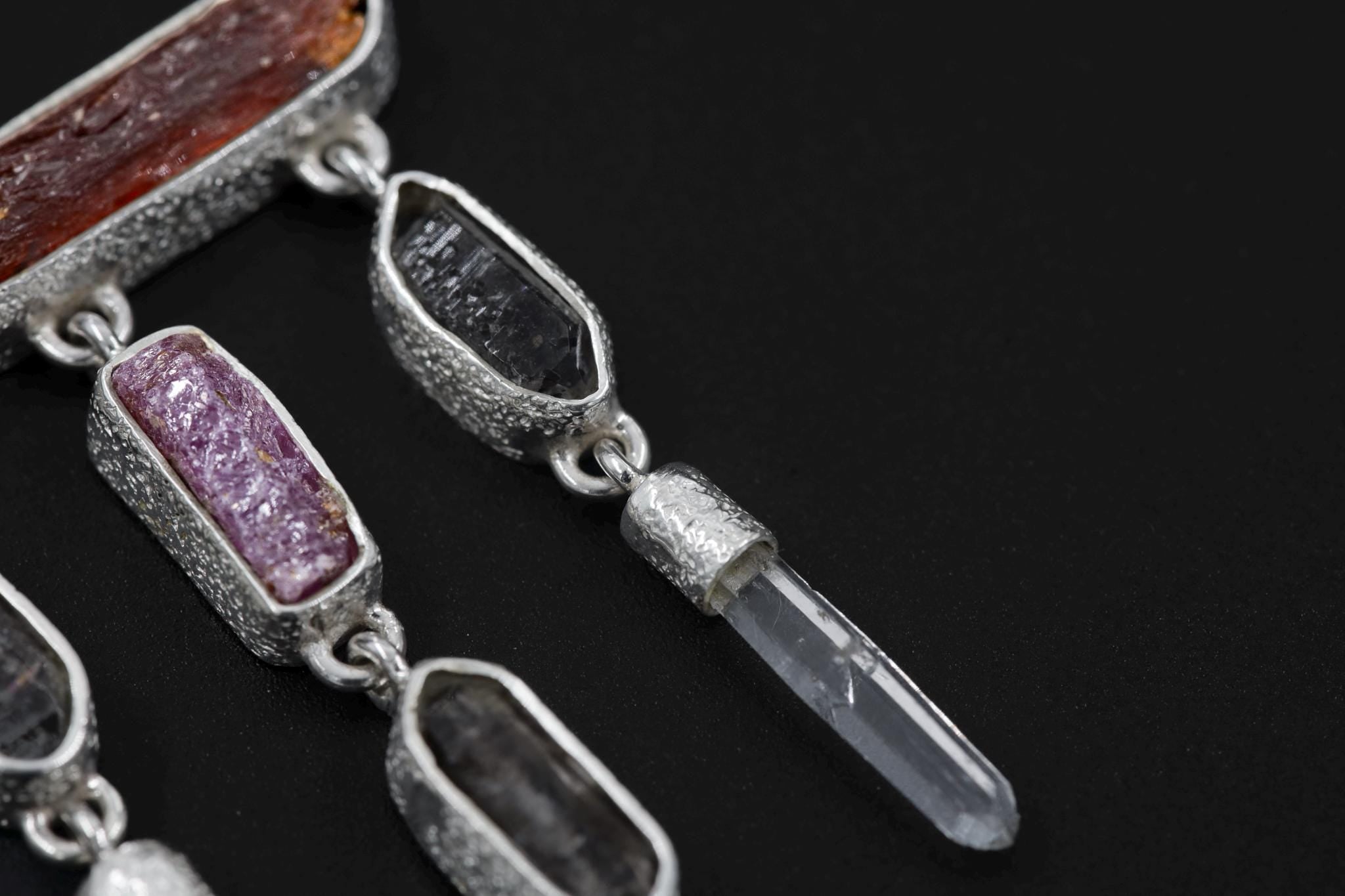 Close-up of Ruby and Petroleum Smoky Quartz beside Red Kyanite and Clear Quartz dangles in an organic silver setting.