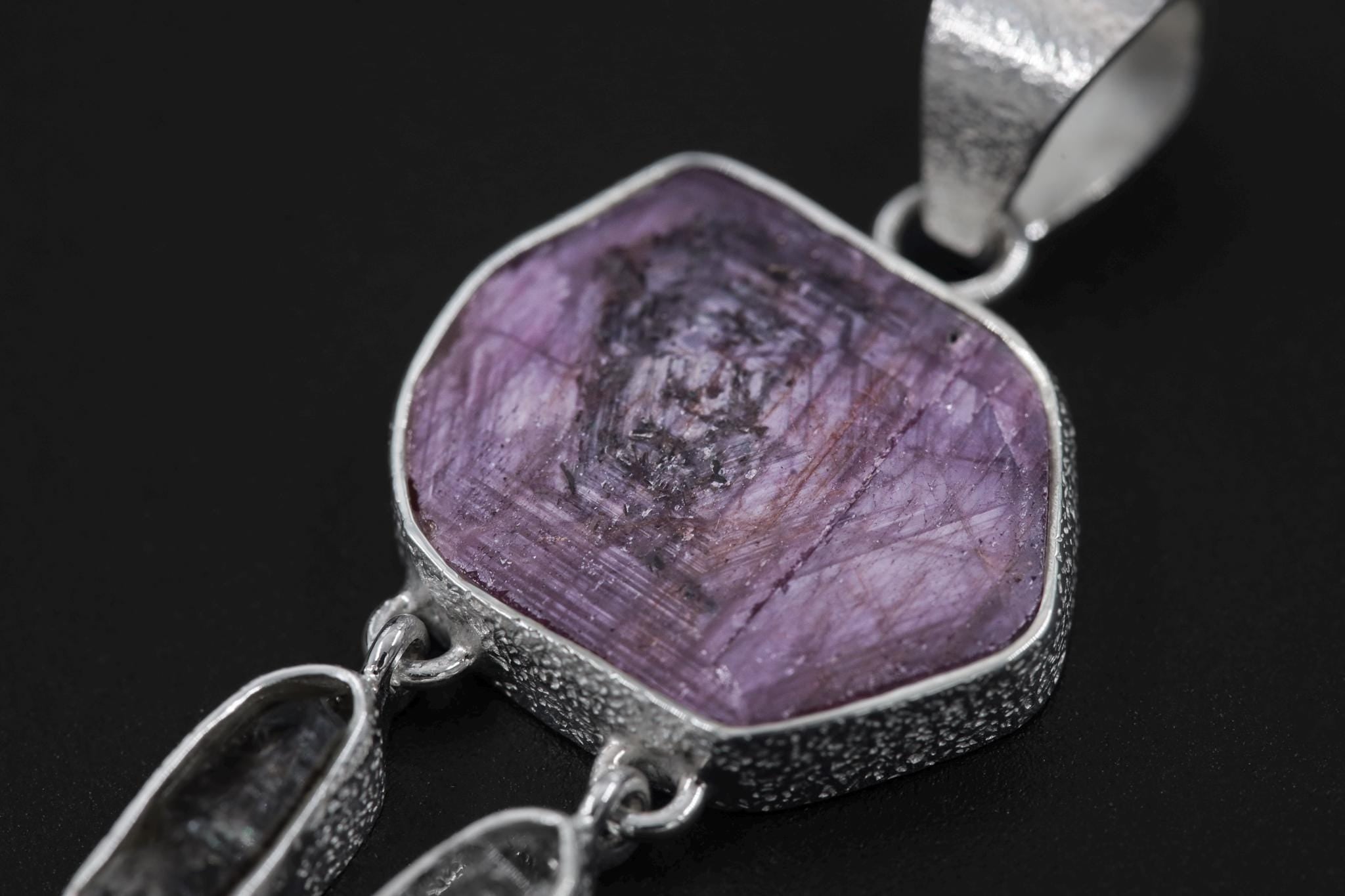 Close-up of raw Gem Ruby and Petroleum Smoky Quartz in a sterling silver dreamcatcher-inspired pendant.