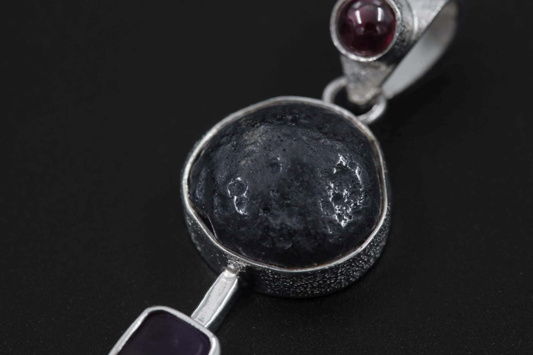 Close-up of raw Tektite centre stone and polished Garnet crown in a 925 sterling silver Celestial Impact pendant.