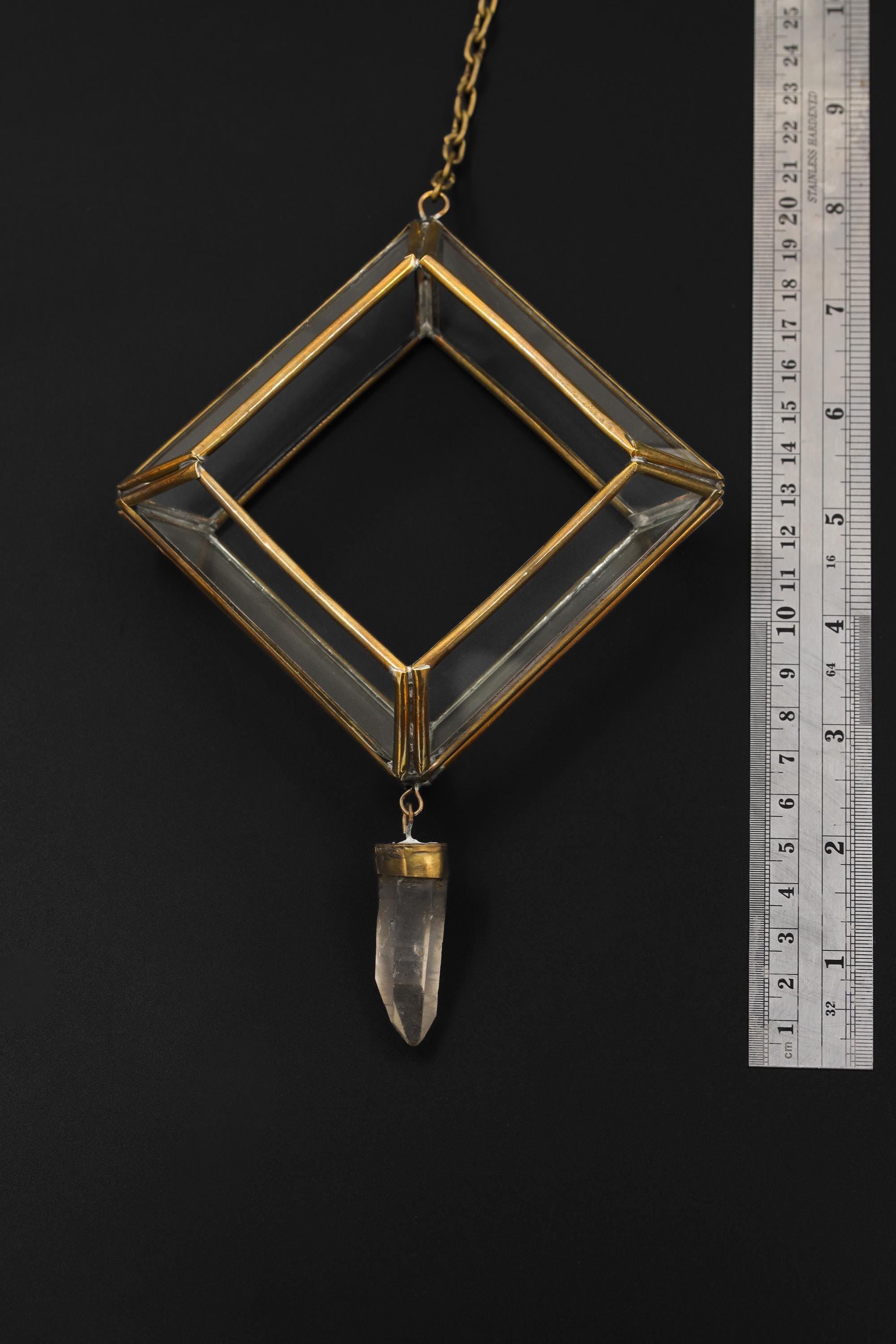 Quartz Reliquary hanging ornament shown beside a ruler for scale with rectangular glass frame and crystal point.
