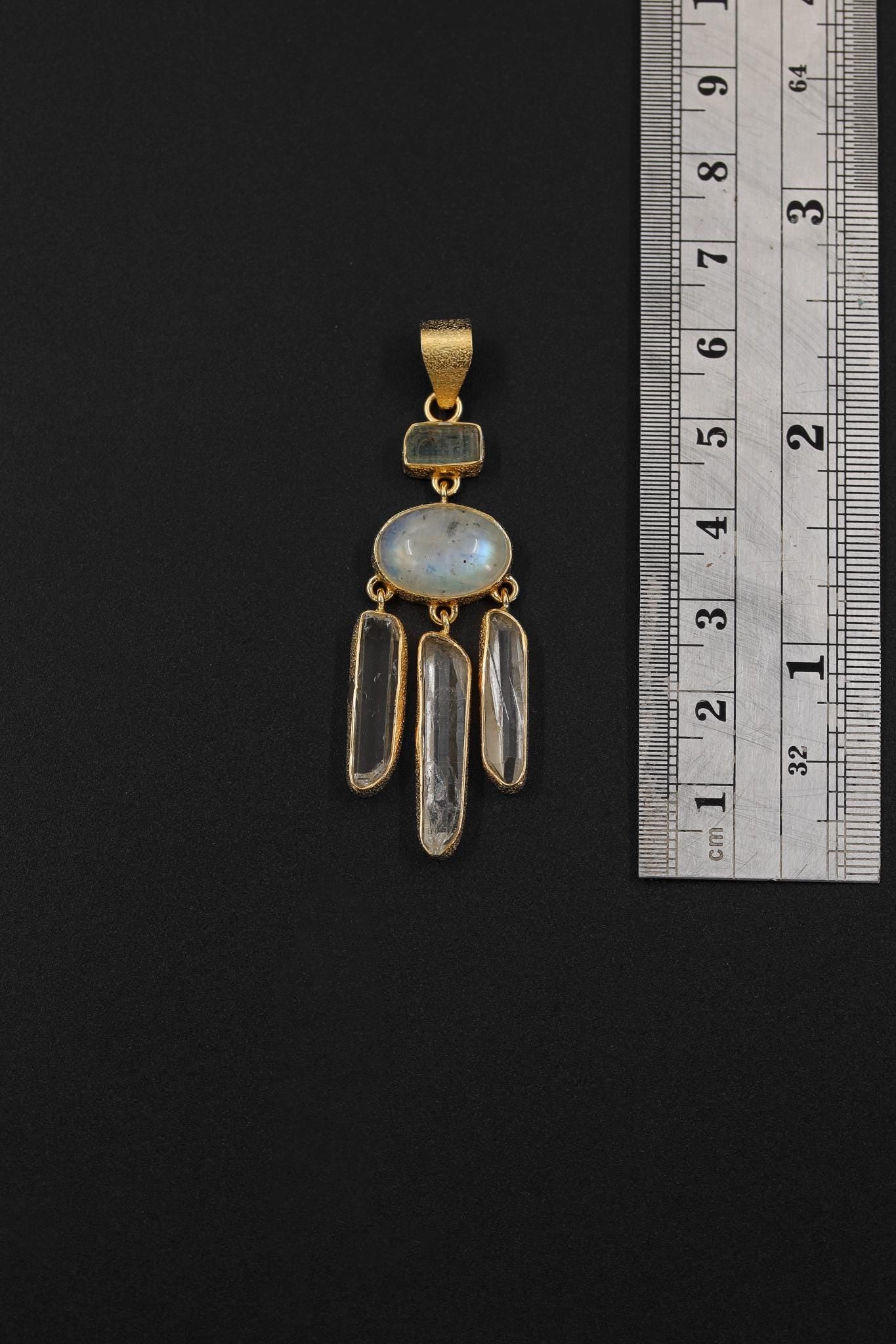 Aquamarine Blue Moonstone Clear Quartz pendant shown beside a ruler for scale, measuring approximately 5.5 to 6 cm long.