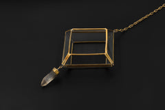 Quartz Reliquary hanging decoration shown on dark background with rectangular brass and glass frame and crystal drop.