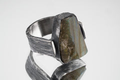 Raw Labradorite ring displayed on white background with brutalist sterling silver setting.