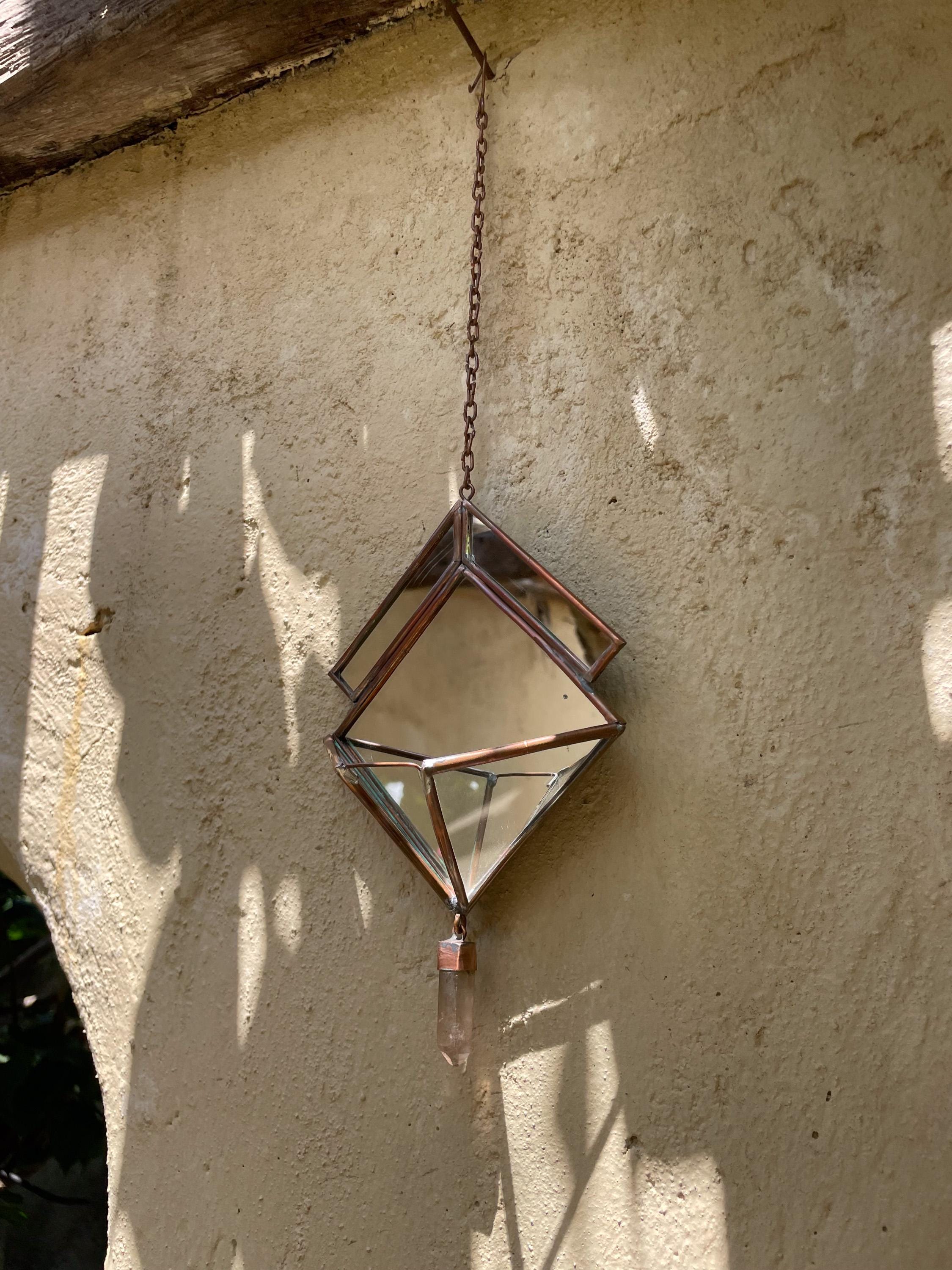 Quartz Reliquary crystal sun catcher hanging on wall with mirrored glass panels reflecting soft natural light.