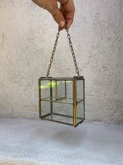 Large brass glass display box held by chain, showing rectangular shape and two-level interior shelf.