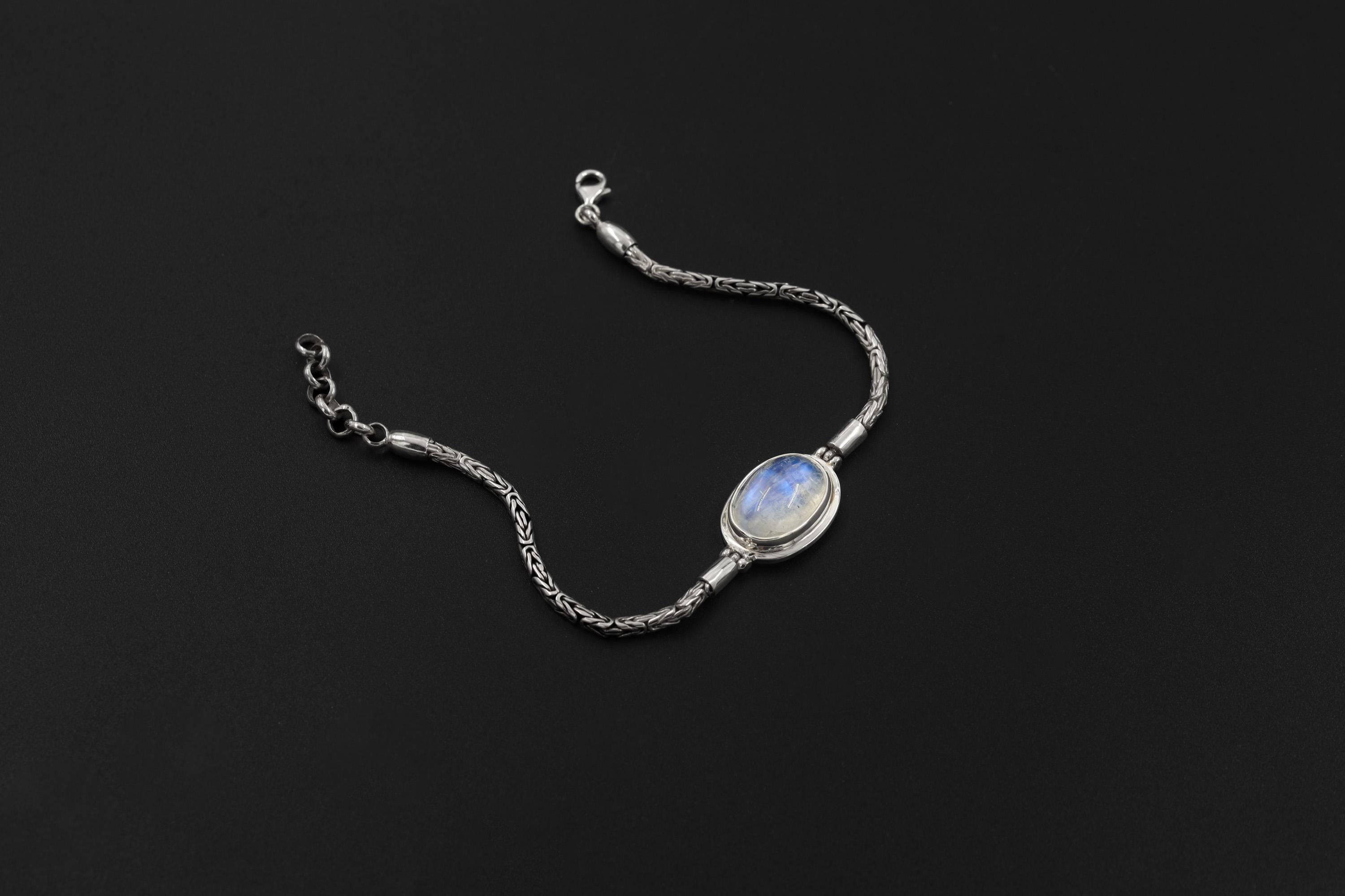 Blue Moonstone bracelet displayed on dark background with oval cabochon and detailed sterling silver Byzantine chain.