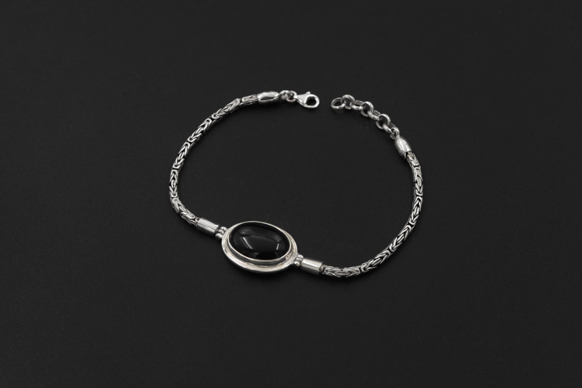 Black Onyx sterling silver Byzantine bracelet shown on dark background beside a ruler for adjustable length reference.