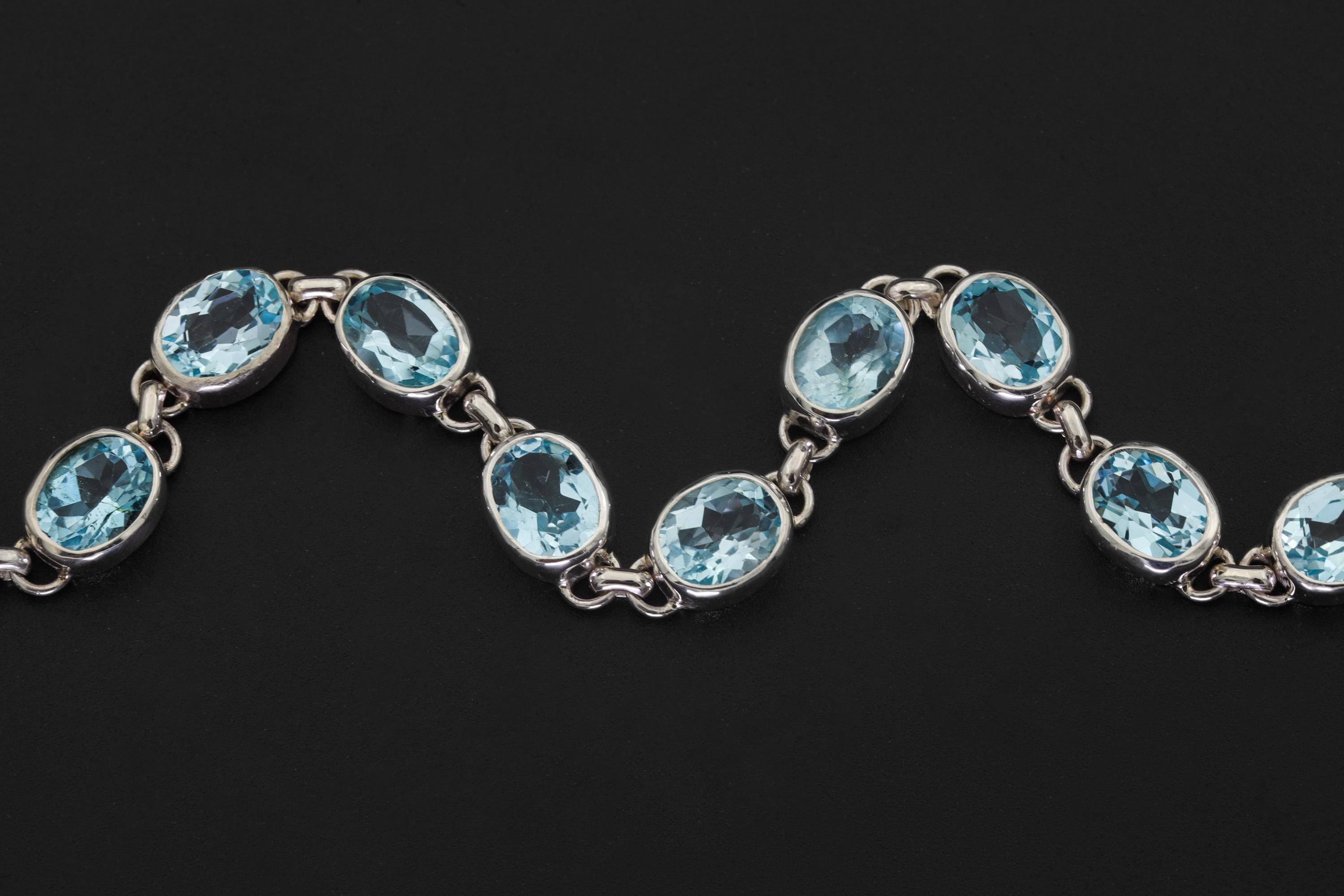 Close view of Blue Topaz bracelet showing faceted sky-blue stones in polished sterling silver bezels.