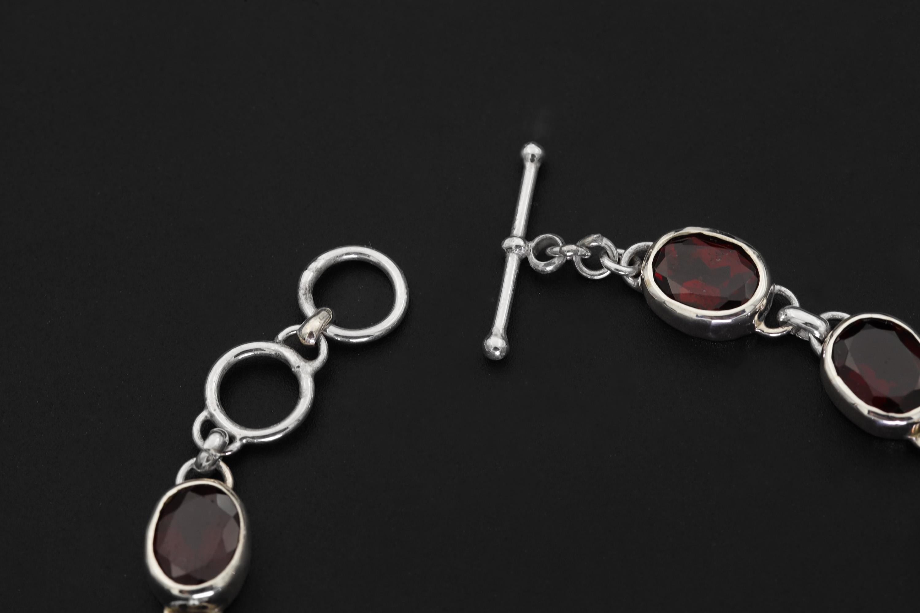 Close view of Garnet bracelet showing faceted red stones and sterling silver toggle clasp detail.