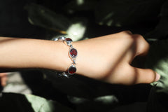 Garnet sterling silver bracelet shown worn on the wrist with deep red faceted gemstones.
