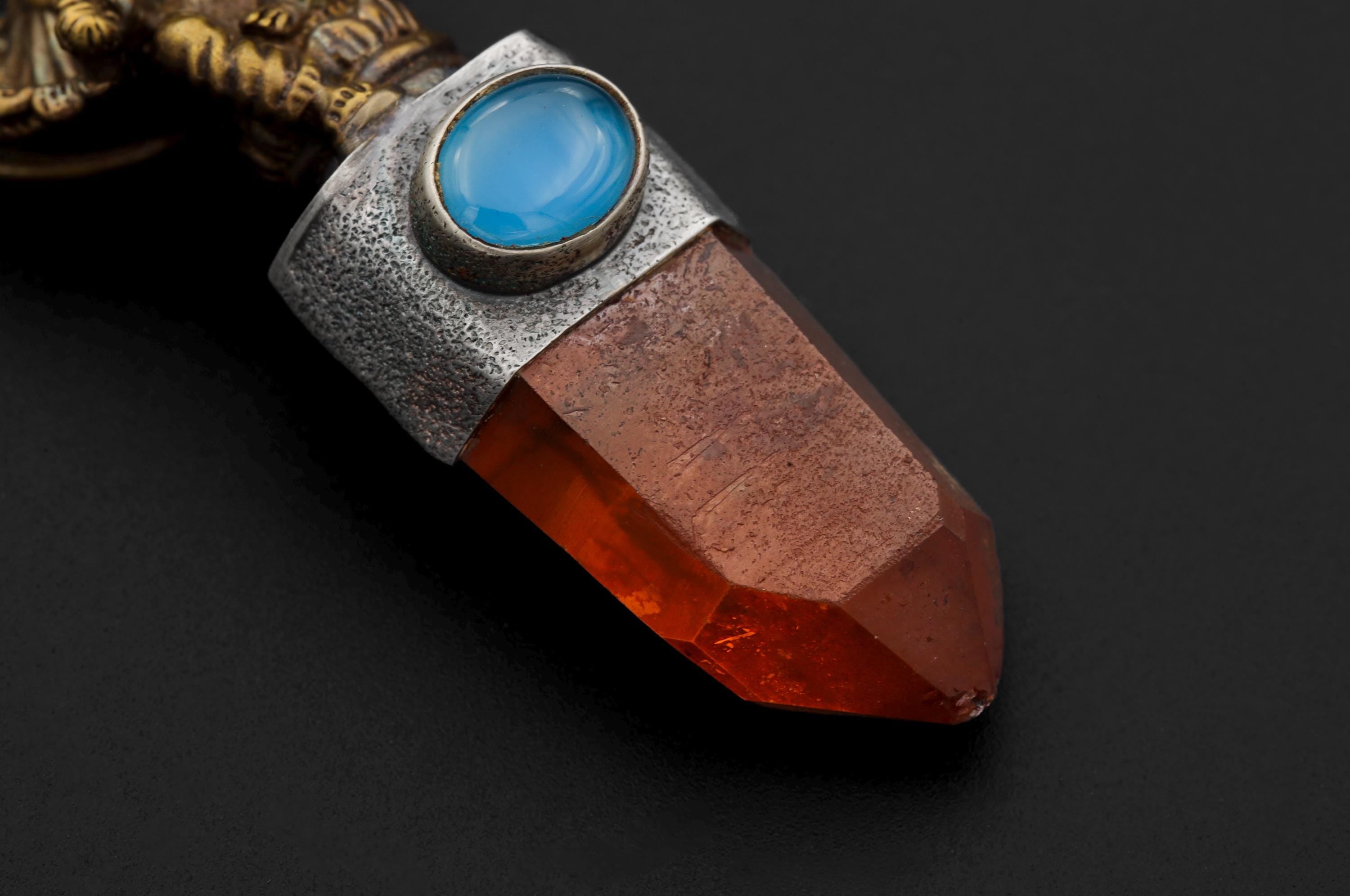 Close-up of Australian Lithium Finger Quartz point beneath Aquamarine in a gold-plated Ganesha talisman pendant.