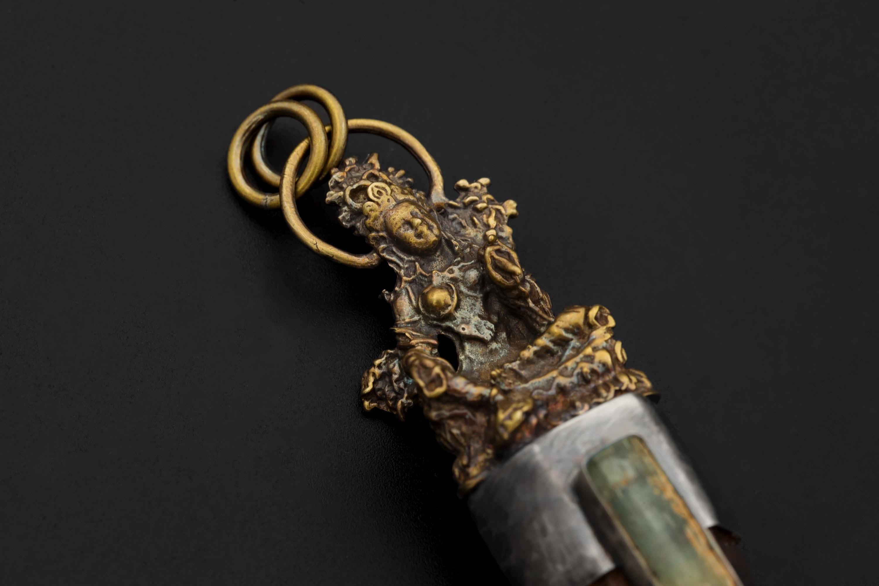 Pendant laid flat revealing oxidized texture on silver bezel and intricate Saraswati casting details.